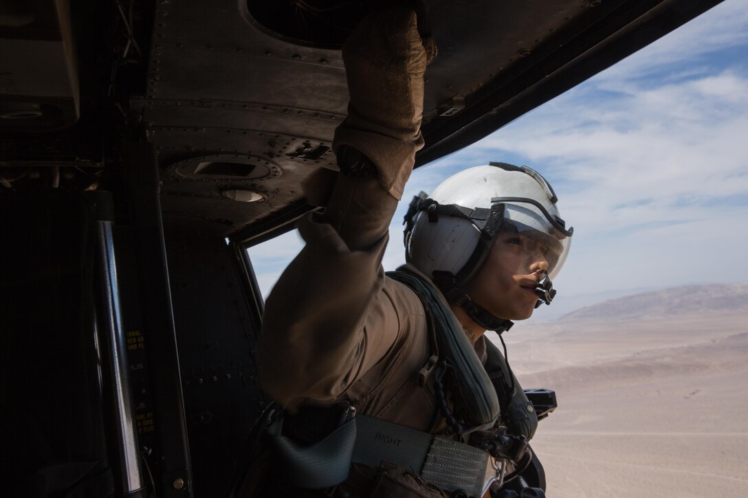 Lance Cpl. Servando Avila, a crew chief with Marine Light Attack Helicopter Squadron (HMLA) 267 “Stingers” and a Houston native, looks out the door of a UH-1Y Huey during a flight over Marine Corps Air Ground Combat Center Twentynine Palms, Calif., June 10. Marines with HMLA-267 supported Marines with 3rd Battalion, 7th Marine Regiment, during a close-air-support training mission aboard the combat center. (U.S. Marine Corps photo by Sgt. Lillian Stephens/Released)