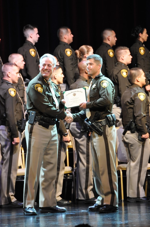 Tech. Sgt. Jonathan Carrington, 926th Aircraft Maintenance Squadron, receives his certificate from Sheriff Joseph Lombardo, during the Las Vegas Metropolitan Police Department's academy graduation ceremony June 14. Carrington is an F-16 weapons loader in the Air Force Reserve.