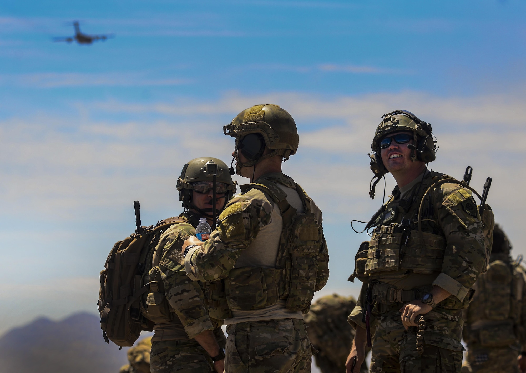 Multiple Joint Terminal Attack Controllers and Combat Controllers watch C-130s fly in formation during the Joint Forcible Entry Exercise portion of the United States Air Force Weapons School Advanced Integration, June 16, 2016. Joint service exercises like the JFEX are integral to maintaining operational cohesiveness between the Air Force and the Army. (U.S. Air Force photo by Airman 1st Class Kevin Tanenbaum)