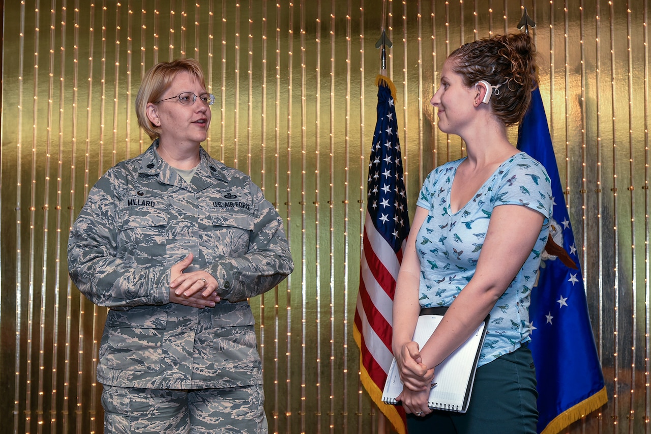 PETERSON AIR FORCE BASE, Colo. – Rachael McAnallen, 21st Civil Engineer Squadron environmental program manager, right, accepts a position as the 21st Space Wing, Wing Staff Agency key spouse representative from Lt. Col. Christine Millard, 21st Comptroller Squadron commander, during a WSA all call at the Peterson Club on June 14, 2016. McAnallen was born deaf and uses technology to help communicate with peers and other key spouses. (U.S. Air Force photo by Craig Denton)