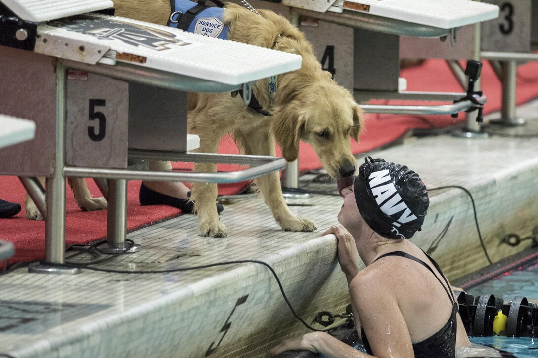 Navy Petty Officer 3rd Class Abbie Johnson gets a kiss from Kona, her military service dog, after competing in a swimming during the 2016 Department of Defense Warrior Games at the U.S. Military Academy in West Point, N.Y., June 20, 2016. DoD photo by Roger Wollenberg