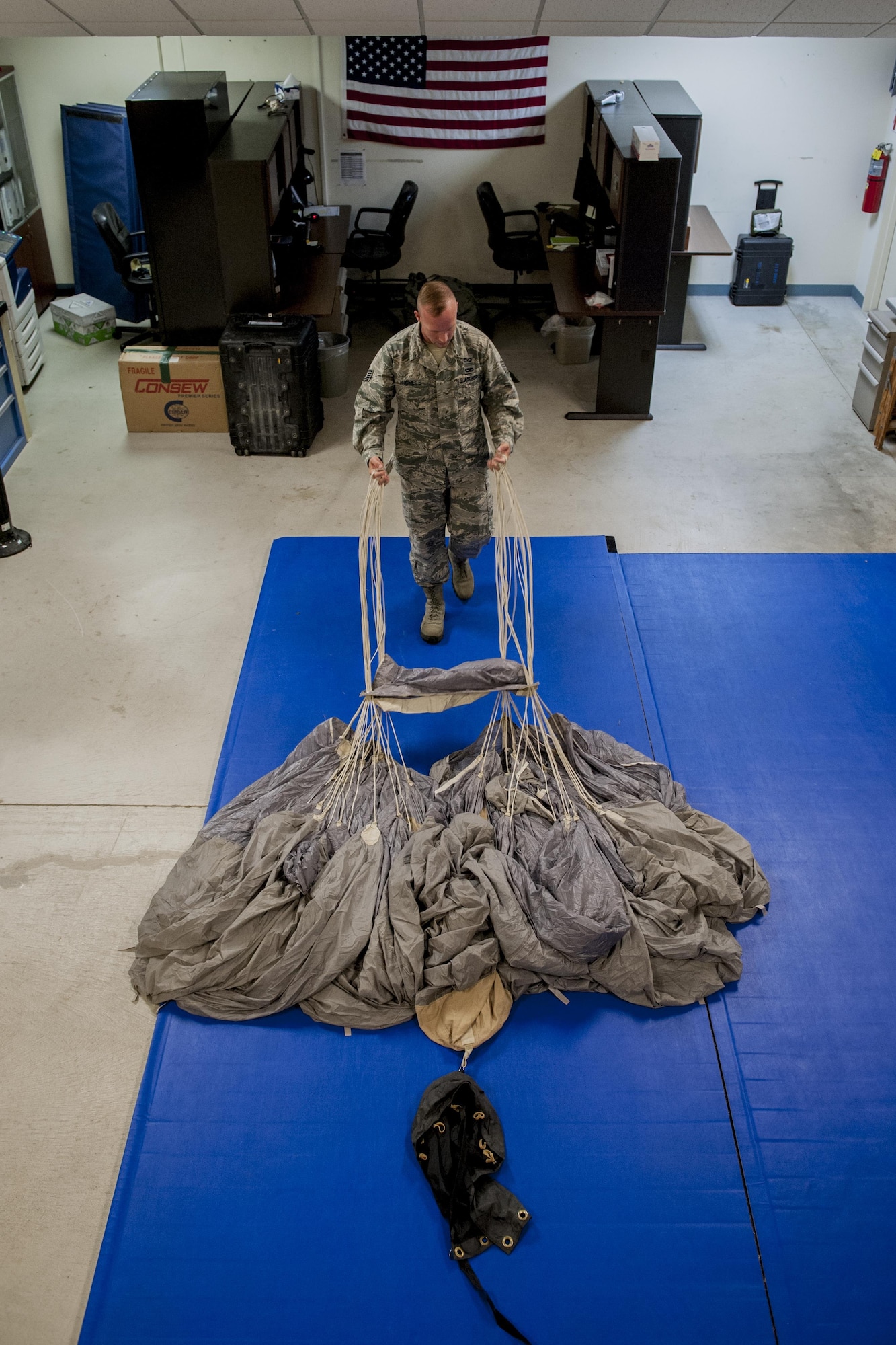 U.S. Air Force Tech. Sgt. Matthew Michels, 31st Rescue Squadron aircrew flight equipment assistant NCO in charge, straightens parachute chords while parachute packing June 20, 2016, at Kadena Air Base, Japan. Michels ensures 31st RQS pararescuemen can don safe parachute packs that have passed intensive safety checks. (U.S. Air Force photo by Senior Airman Peter Reft)