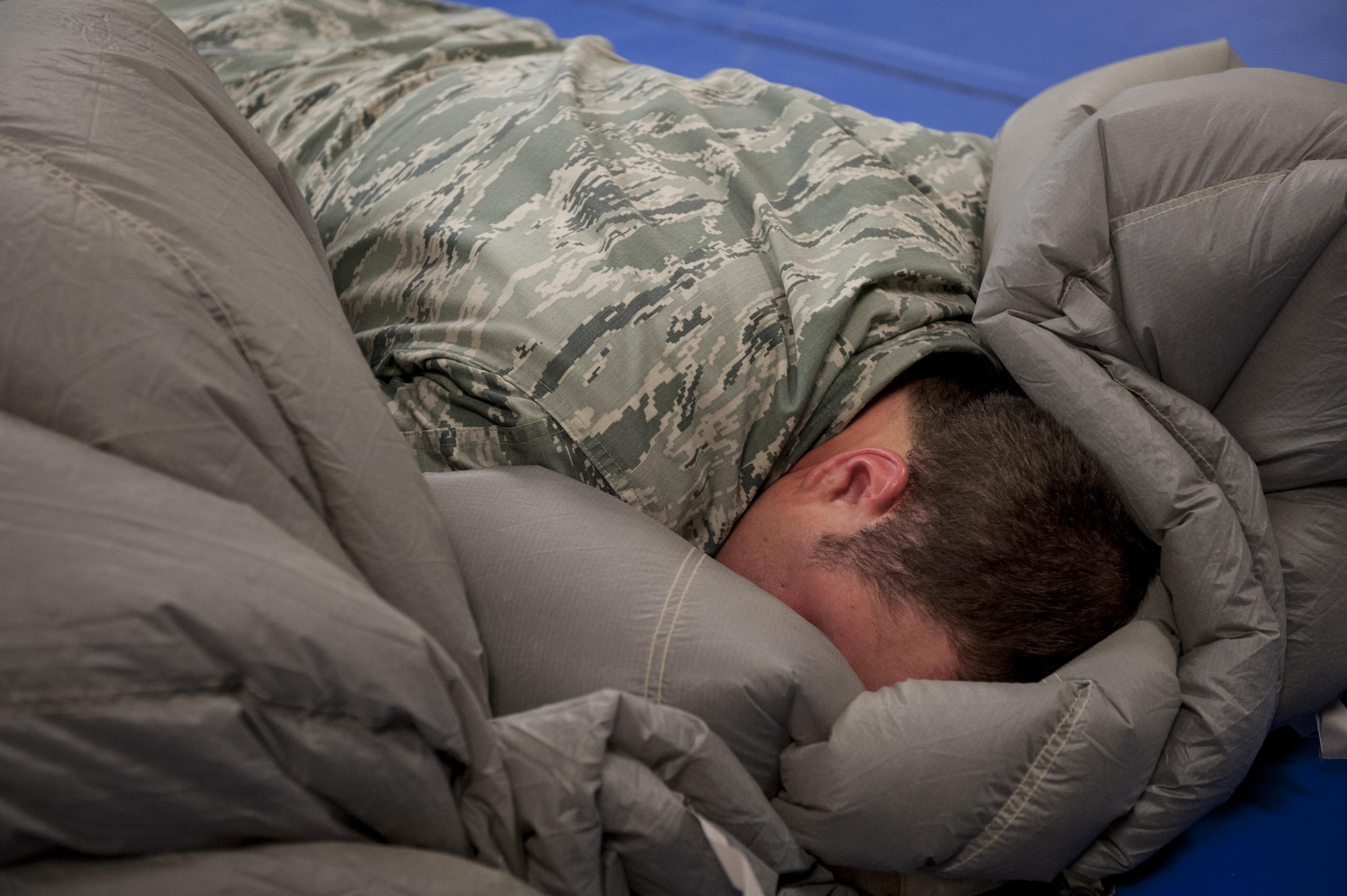 U.S. Air Force Senior Airman Erik Merrill, 31st Rescue Squadron aircrew flight equipment journeyman, cocoons a parachute canopy June 20, 2016, at Kadena Air Base, Japan. Merrill applied his entire body weight on top of the canopy in order to push out all the air between folds, enabling him to pack it into a small deployment bag. (U.S. Air Force photo by Senior Airman Peter Reft)