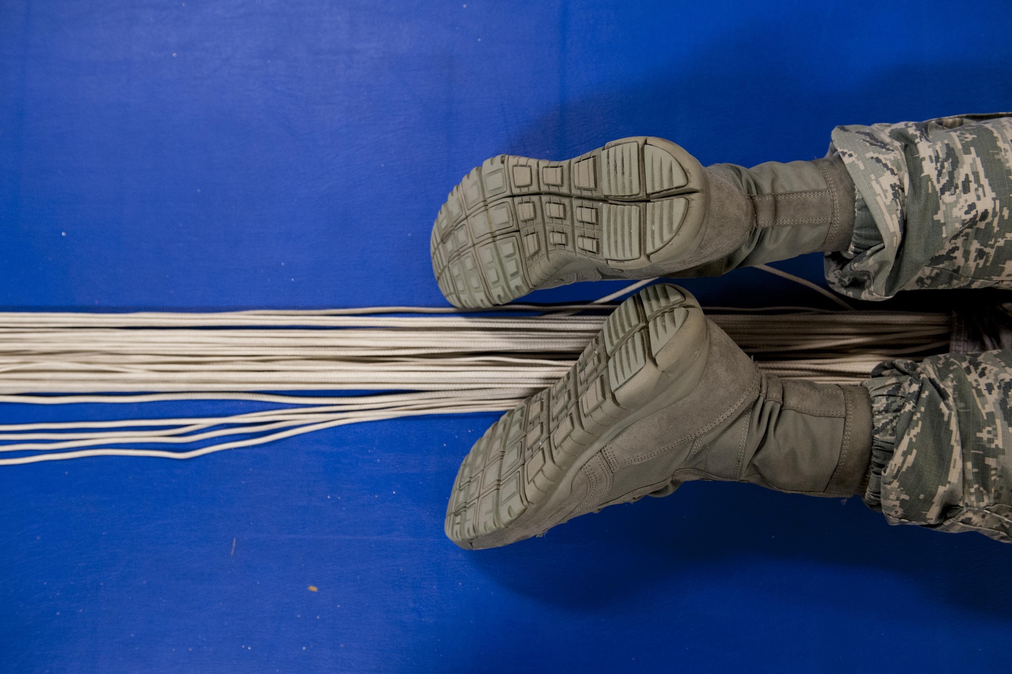 U.S. Air Force Senior Airman Erik Merrill, 31st Rescue Squadron aircrew flight equipment journeyman, cocoons a parachute canopy June 20, 2016, at Kadena Air Base, Japan. In order to push out all the air inside the material for packing, Merrill applied his entire body weight by lying down on top of the canopy. (U.S. Air Force photo by Senior Airman Peter Reft)