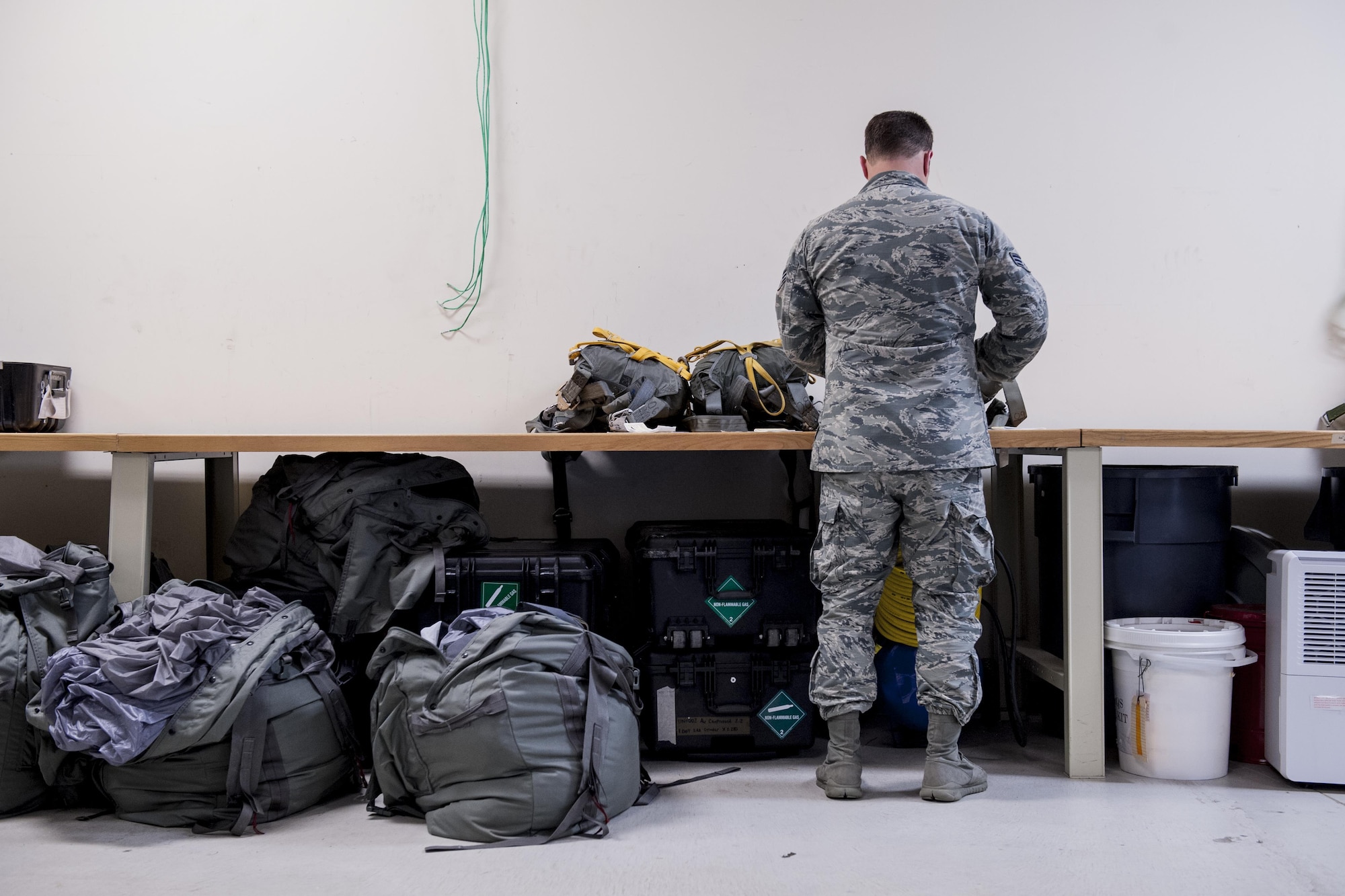 U.S. Air Force Senior Airman Erik Merrill, 31st Rescue Squadron aircrew flight equipment journeyman, inspects equipment June 20, 2016, at Kadena Air Base, Japan. Merrill assembles parachutes for pararescuemen and maintains a variety of aircrew equipment such as oxygen bottles, masks, life preservers, altimeters and night vision goggles. (U.S. Air Force photo by Senior Airman Peter Reft)