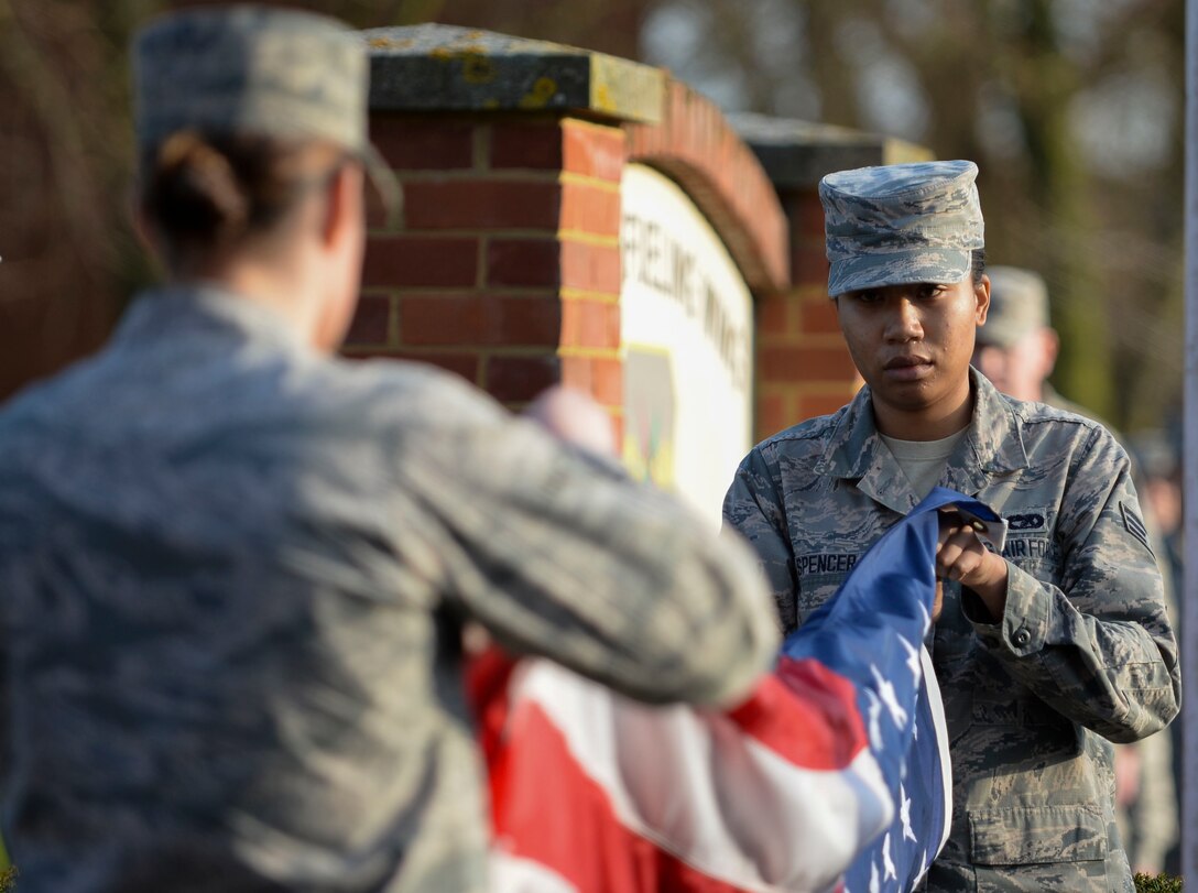 U.S. Air Force Senior Airman Tynisha Spencer, 100th Logistics Readiness Squadron traffic management journeyman, prepares the U.S. flag during a retreat ceremony March 25, 2016, on RAF Mildenhall, England. Spencer has been a member of the base honor guard team since 2014 and has completed more than 250 hours to the program. (U.S. Air Force photo by Senior Airman Victoria Taylor/Released)