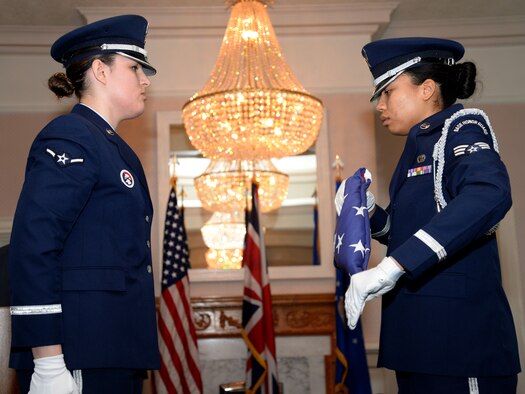 U.S. Air Force Senior Airman Tynisha Spencer, right, 100th Logistics Readiness Squadron traffic management journeyman, prepares the U.S. flag during a retirement ceremony April 7, 2016, on RAF Mildenhall, England. Spencer has been a member of the base honor guard team since 2014 and has completed more than 250 hours to the program. (U.S. Air Force photo by Senior Justine Rho/Released)