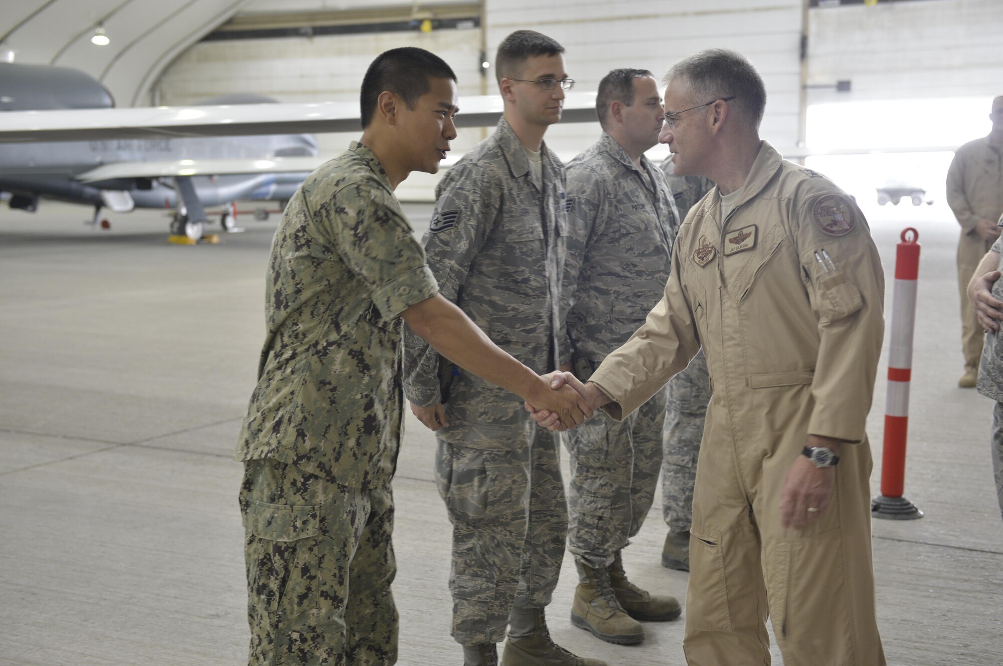 Maj. Gen. Jay Silveria, Deputy Commander, Combined Air Force Air Component, U.S. Central Command, shakes hands with U.S. Navy Lt. Cmdr. Long, 380th Expeditionary Aircraft Maintenance Squadron, during a tour of the Global Hawk facility at an undisclosed location in Southwest Asia June 18. Silveria toured several facilities and interacted with the men and women behind the 380th Air Expeditionary Wing mission. (U.S. Air Force photo by Tech. Sgt. Chad Warren)