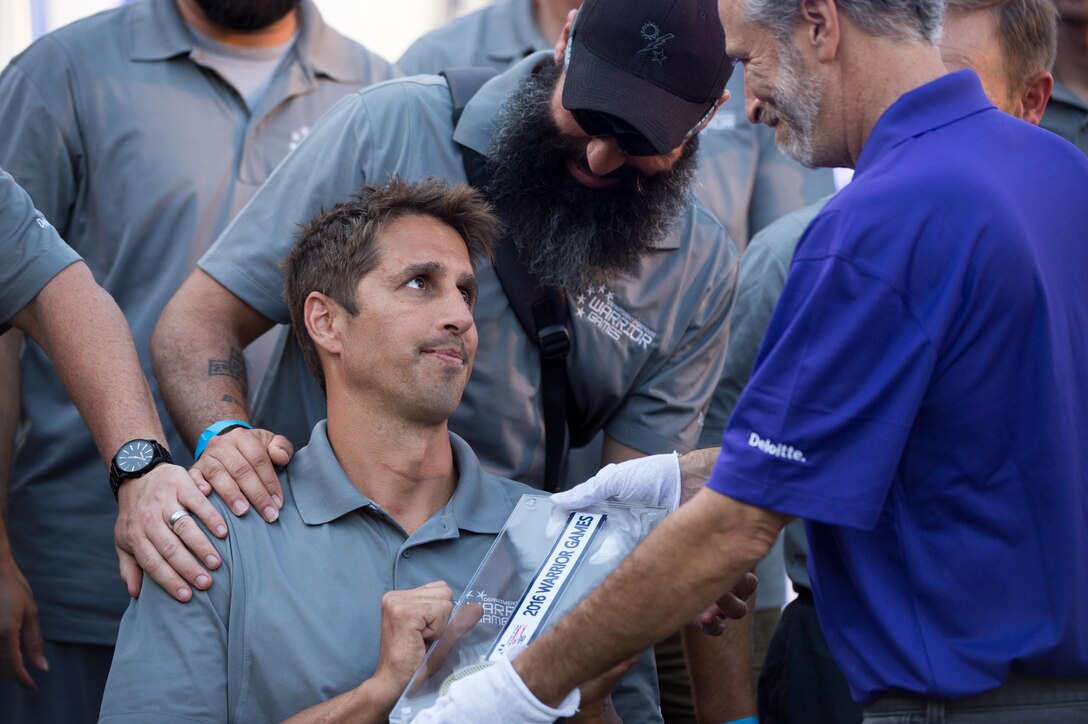 Navy Lt. Ramesh Haytasingh, a member of the U.S. Special Operations Command team, accepts the Heart of the Team Award for his team from comedian Jon Stewart during the closing ceremony for the 2016 Department of Defense Warrior Games at the U.S. Military Academy in West Point, N.Y., June 21, 2016. DoD photo by EJ Hersom