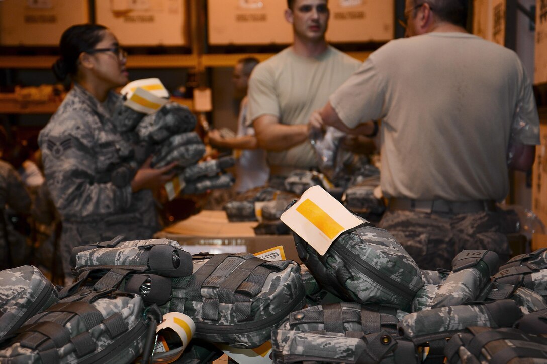 Members of the 379th Expeditionary Medical Support Squadron take joint first aid kits (JFAK) out of their respective boxes for inspection at Al Udeid Air Base, Qatar, June 15, 2016. The 379th EMSS has hosted several JFAK inspecting and building events as a way to expedite the process and get the kits to deployed members faster. (U.S. Air Force photo by Senior Airman Kimberly Nagle)