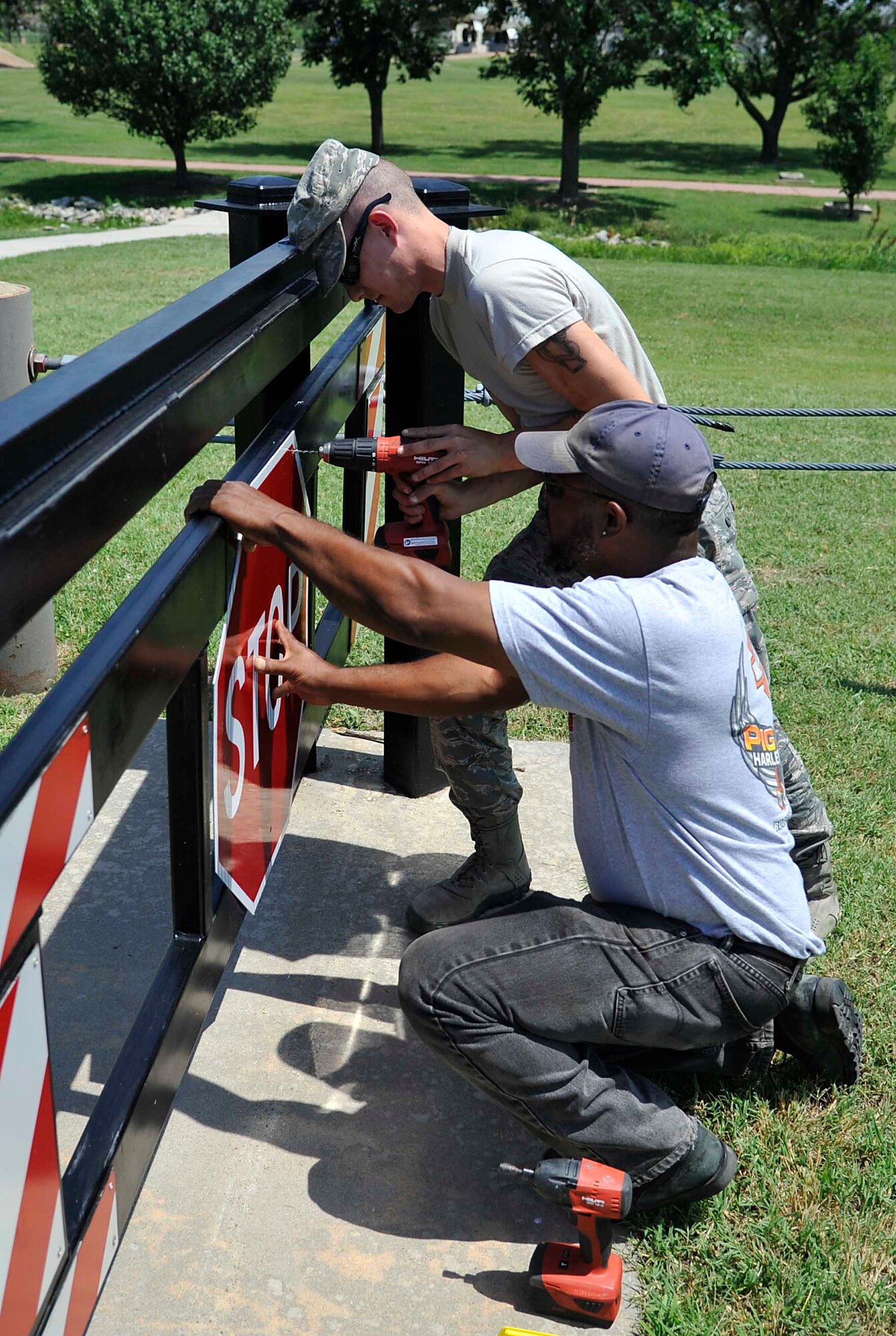 Airman 1st Class James Ori, 22nd Civil Engineer Squadron structures apprentice, and Marshall Townsend, 22nd CES maintenance mechanic, replace signs on serpentine barriers at the main gate, June 21, 2016, at McConnell Air Force Base, Kan. Having barriers at the gate helps increase safety and security on the base. (U.S. Air Force photo/Airman Erin McClellan)