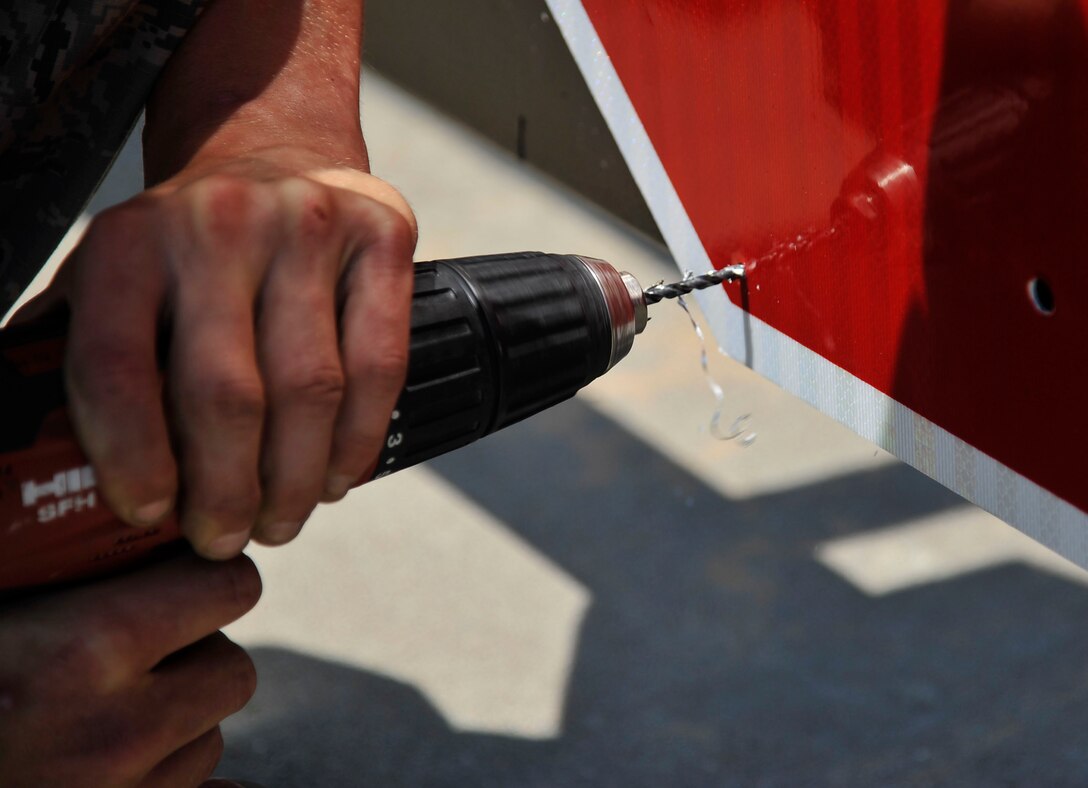 Airman 1st Class James Ori, 22nd Civil Engineer Squadron structures apprentice, replaces signs on serpentine barriers at the main gate, June 21, 2016, at McConnell Air Force Base, Kan. Barriers at the gate are used to help maintain safety and security on the base. (U.S. Air Force photos/Airman Erin McClellan)