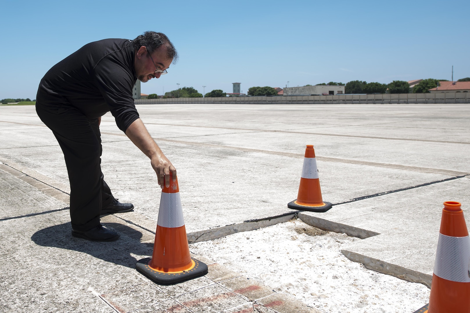 Jack Syers, 12th Operations Support Squadron airfield management operations manager, examines a damaged area of concrete on the flightline during an airfield inspection at Joint Base San Antonio-Randolph June 16, 2016. During airfield inspections, Syers ensures areas of concrete that are cracked or in need of repair are properly marked, as well as surveys for FOD, or foreign object debris.