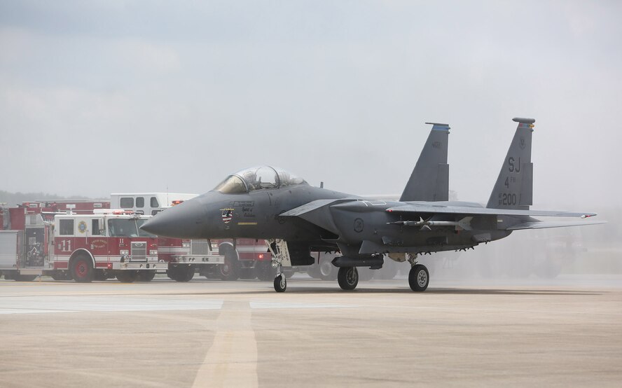 Col. Mark Slocum, 4th Fighter Wing commander, taxis through a wall of water sprayed by the base’s fire trucks, June 16, 2016, at Seymour Johnson Air Force Base, North Carolina. One of the rituals performed for a “fini-flight” is to shower the jet of the departing service member. (Courtesy Photo/Casey Mozingo/Goldsboro News-Argus)