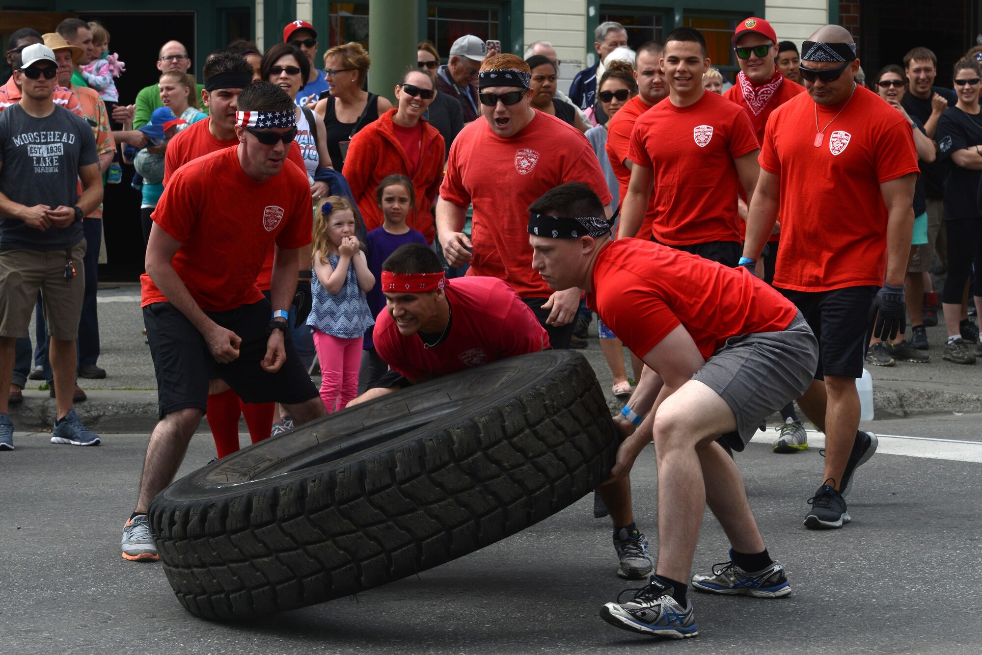 Two members of the ‘Firedawgs,’ Joint Base Elmendorf-Richardson Fire Department team, flip a tire as part of the Hero Games during the Downtown Summer Solstice Festival in Anchorage, Alaska, June 18, 2016. Each team chose two members to flip a tire across a set distance then roll it back. The Hero Games is a friendly competition between Alaska’s first responders with challenges that require balance, strength and teamwork. (U.S. Air Force photo Airman 1st Class Christopher R. Morales)
