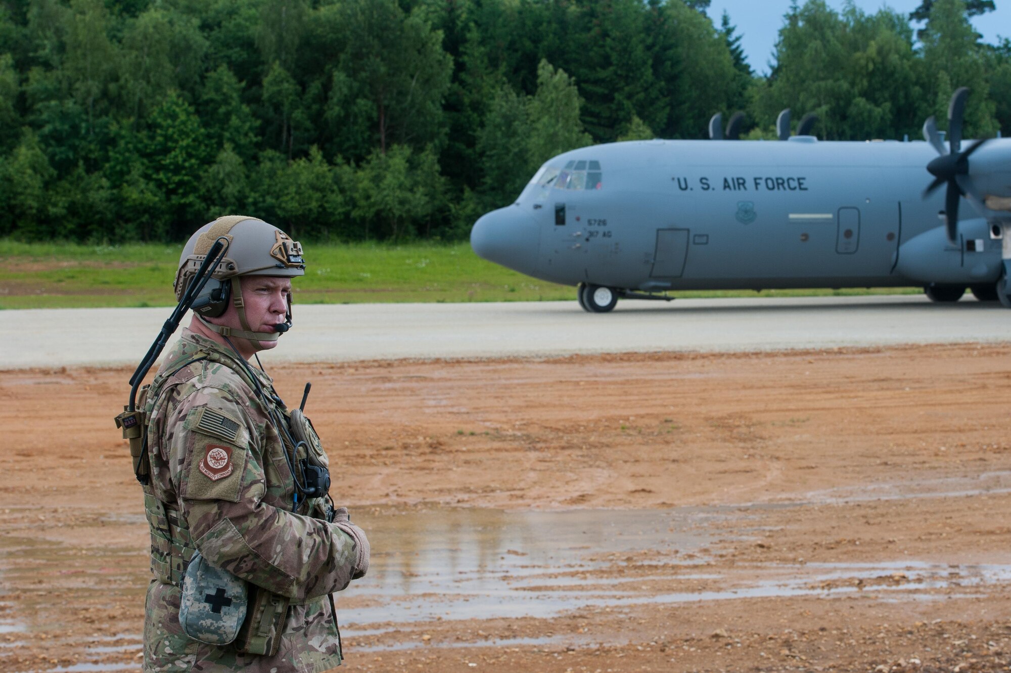 U.S. Air Force Maj. Aaron Cook, 621st Mobility Support Operations Squadron Air Mobility Liaison Officer to the 2nd Cavalry Regiment/Joint Multinational Training Center, radios a U.S. Air Force C-130J Super Hercules pilot while the aircraft is being downloaded during Exercise Swift Response 16 at Hohenfels Training Area, Germany, June 17, 2016. Exercise SR16 is one of the premier military crisis response training events for multinational airborne forces in the world, the exercise has more than 5,000 participants from 10 NATO nations. (U.S. Air Force photo by Master Sgt. Joseph Swafford/Released) 
