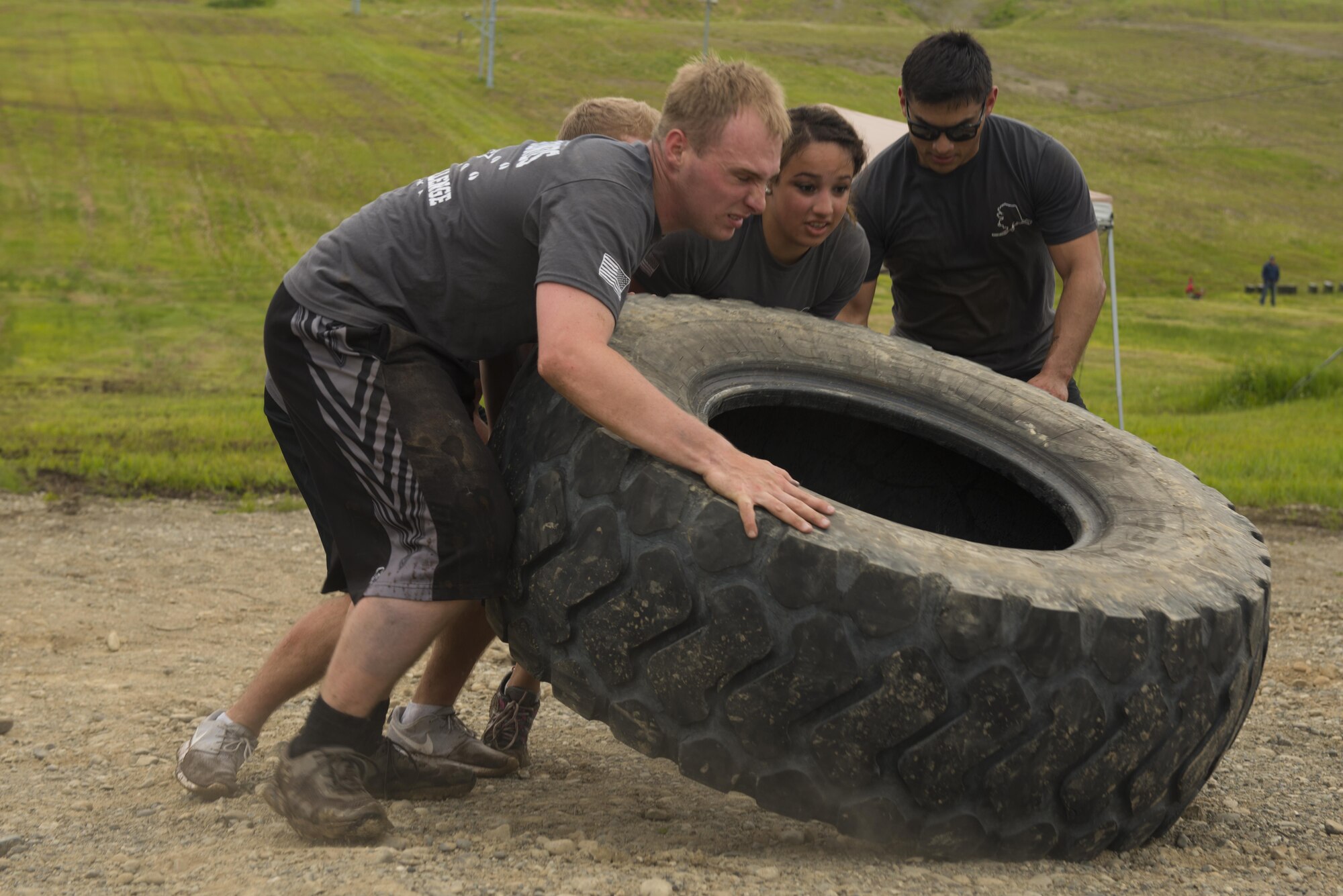 Airman 1st Class Dakotah Steele, a 673d Communications Squadron radio frequency transmissions technician from Neosho, Mo., and his team flip a tire repeatedly as the last challenge of the Dirty Dozen June 10. Each team had four participants who made their way through 12 physical, intellectual and tactical challenges in a contest to best the other team's times. (U.S. Air Force photo by Senior Airman Kyle Johnson)
