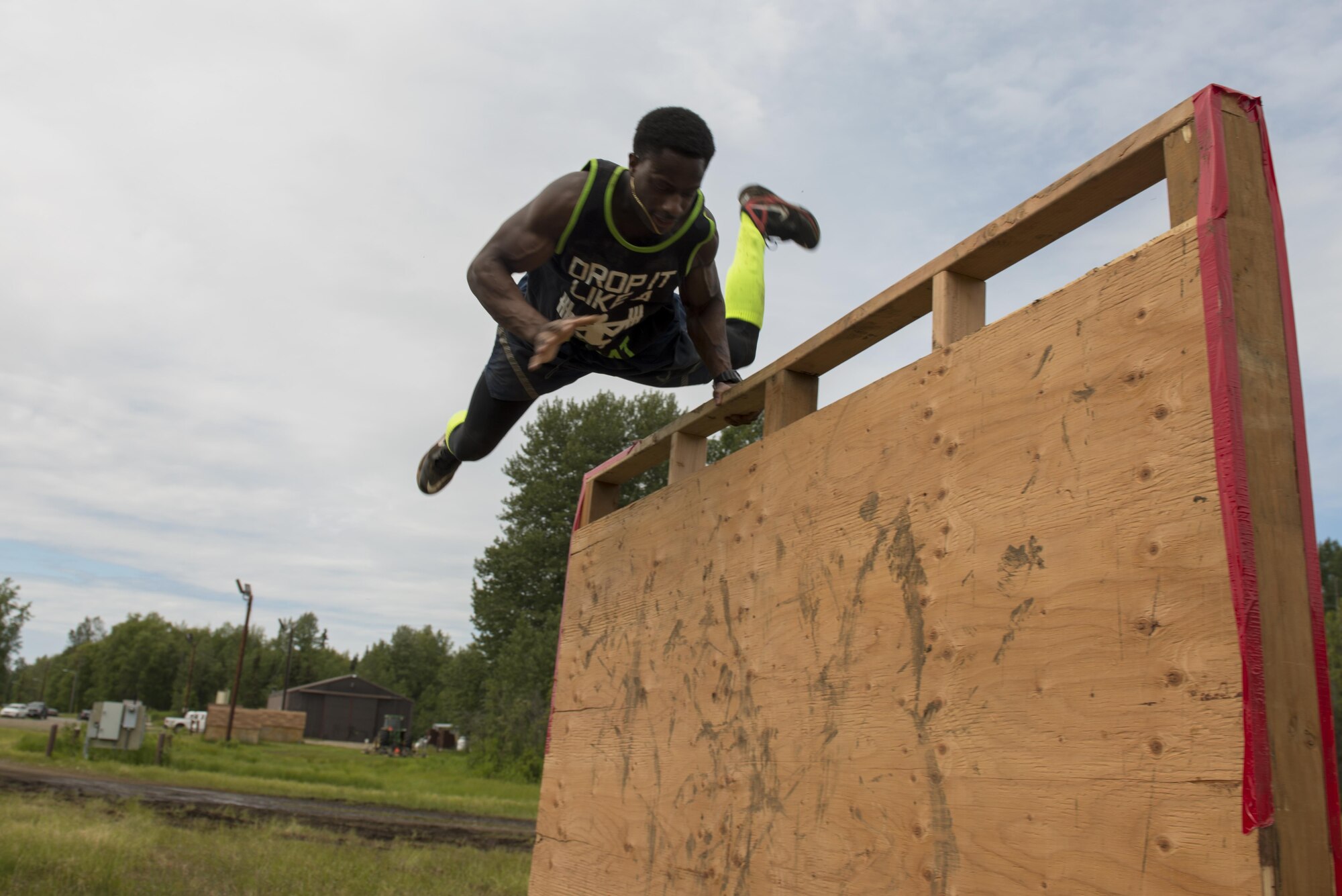 Senior Airman Ricky Jones, a 962nd Airborne Air Control Squadron communications technician and Mesena, Georgia native flings himself over a wooden wall as part of the Dirty Dozen challenge June 10. Dirty Dozen is a chain of 12 stations, each testing the team's competency in intellectual and physical challenges. Jones' team, 'Rub Some Dirt on It' placed second overall. (U.S. Air Force photo by Senior Airman Kyle Johnson)