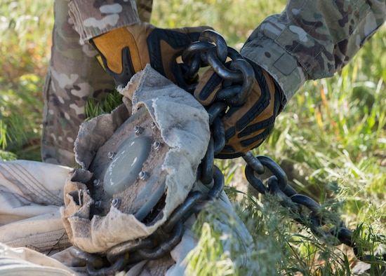 An airman from the 366th Civil Engineer Squadron wraps a chain around an inert GBU-12 Paveway II's parachute in preparation for removal during a range clearance at Saylor Creek Range Complex, Idaho, May 9, 2016. The 366th Fighter Wing at Mountain Home Air Force Base operates, maintains and develops the Mountain Home, Idaho, Range Complex which is comprised of 7,400 square miles of associated airspace and 122,000 acres of land space used for two air-to-ground training ranges, five no-drop target complexes and 30 multi-size electronic combat sites. (U.S. Air Force photo by Airman 1st Class Chester Mientkiewicz/Released)
