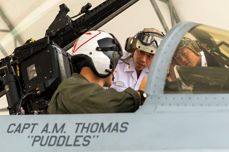 U.S. Marine Corps Capt. Daniel Lane, a pilot with Marine Fighter Attack Squadron (VMFA) 122, shows two Japan Maritime Self-Defense Force aviation officer cadets inside the cockpit of an F/A-18C during a Japanese Officer Exchange Program tour at Marine Corps Air Station Iwakuni, Japan, June 17, 2016. Hosted by Marine Aircraft Group 12, the exchange program aims to better the understanding and working relationships between U.S. and Japanese pilots. During the visit, 30 students from the JMSDF Ozuki Aviation Training Squadron from JMSDF Ozuki Air Base, Shimonoseki, toured the air station to see up close F/A-18C Hornets belonging to Marine Fighter Attack Squadron 122, took turns flying an F/A-18 flight simulator and learned MAG-12’s mission, organization, equipment, operations and flight training. (U.S. Marine Corps photo by Lance Cpl. Aaron Henson/Released)