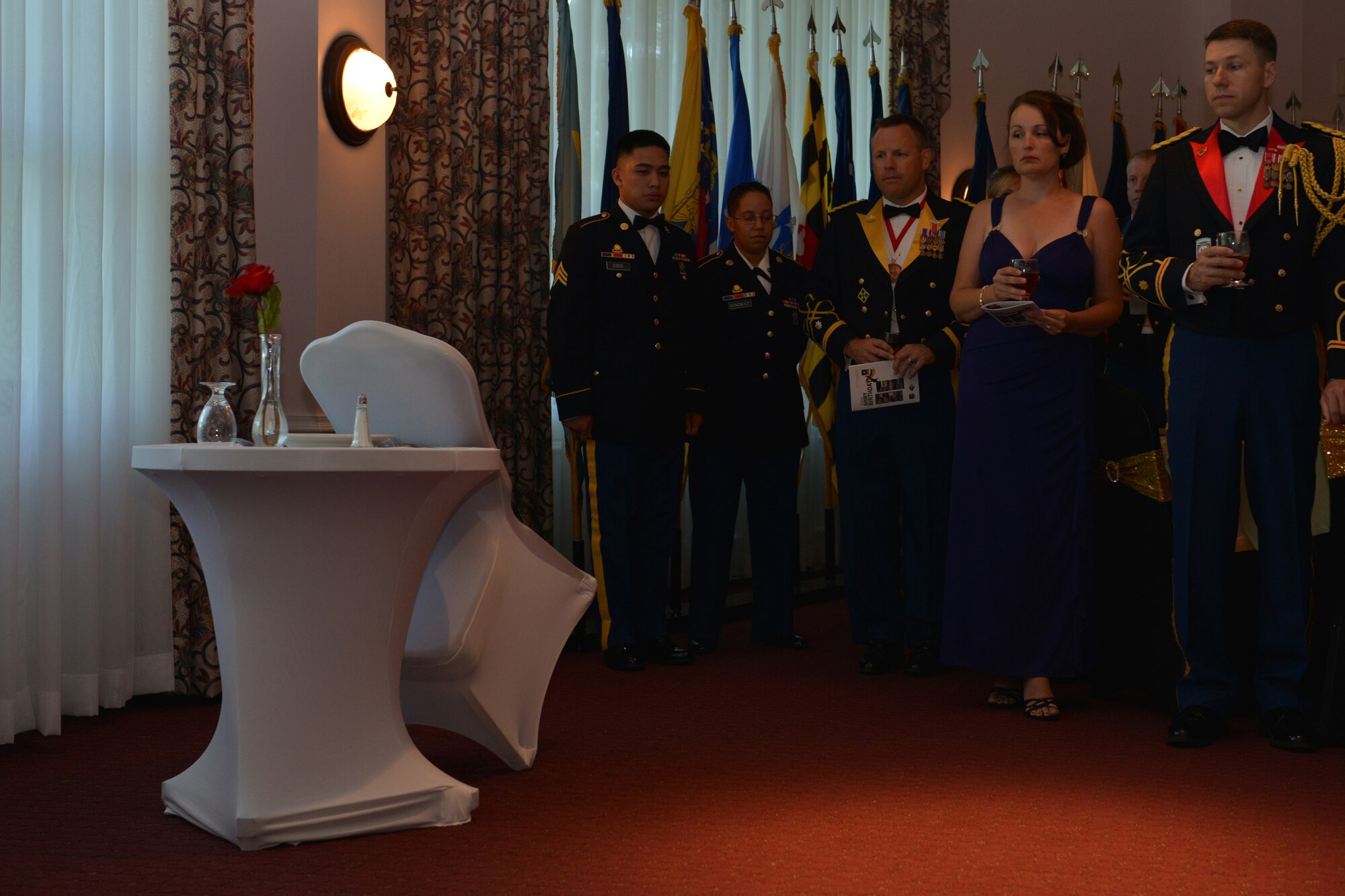 U.S. Service members and their guests take a moment of silence while paying honors to the prisoners of war and missing in action table during the Army Ball at Fort Eustis, Va., June 17, 2016. The tradition of setting a separate table in honor of POW/MIA comrades has been in place since the end of the Vietnam War. (U.S. Air Force photo by Staff Sgt. Natasha Stannard)