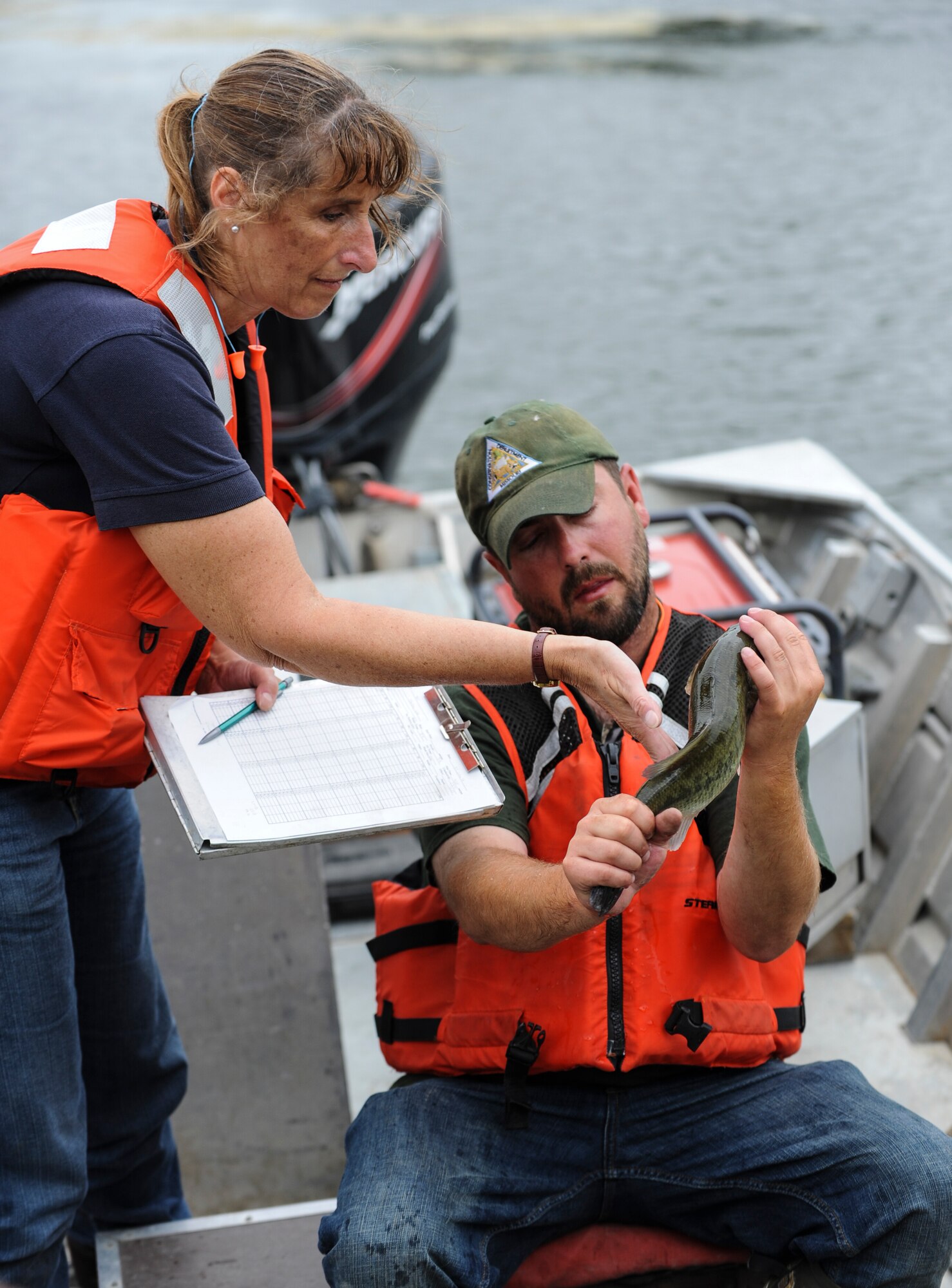 Trish Yasger, left, a fisheries biologist with the Missouri Department of Conservation (MDC), and Ty Cravens, right, a resource assistant with MDC, inspect a fish from the Ike Skelton Lake at Whiteman Air Force Base, Mo., June 21, 2016. The team used electrofishing, which is a scientific survey method designed to sample fish populations to determine abundance, density and species composition. (U.S. Air Force photo by Senior Airman Danielle Quilla)