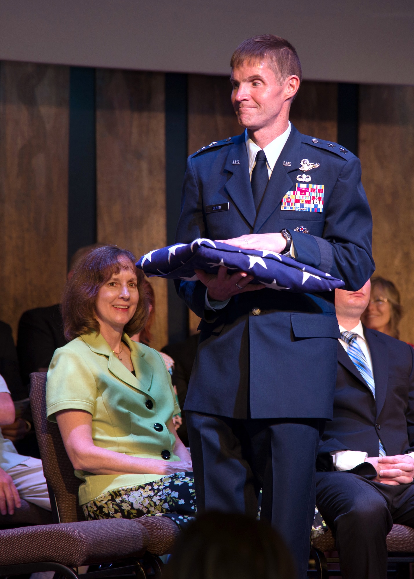Maj. Gen. Craig S. Olson, former C3I and Networks program executive officer, stands with the American flag following a flag folding ceremony during his retirement ceremony June 17 at the Genesis Church in Woburn, Mass. Olson is retiring after serving 34 years in the United States Air Force. (U.S. Air Force photo by Mark Herlihy)