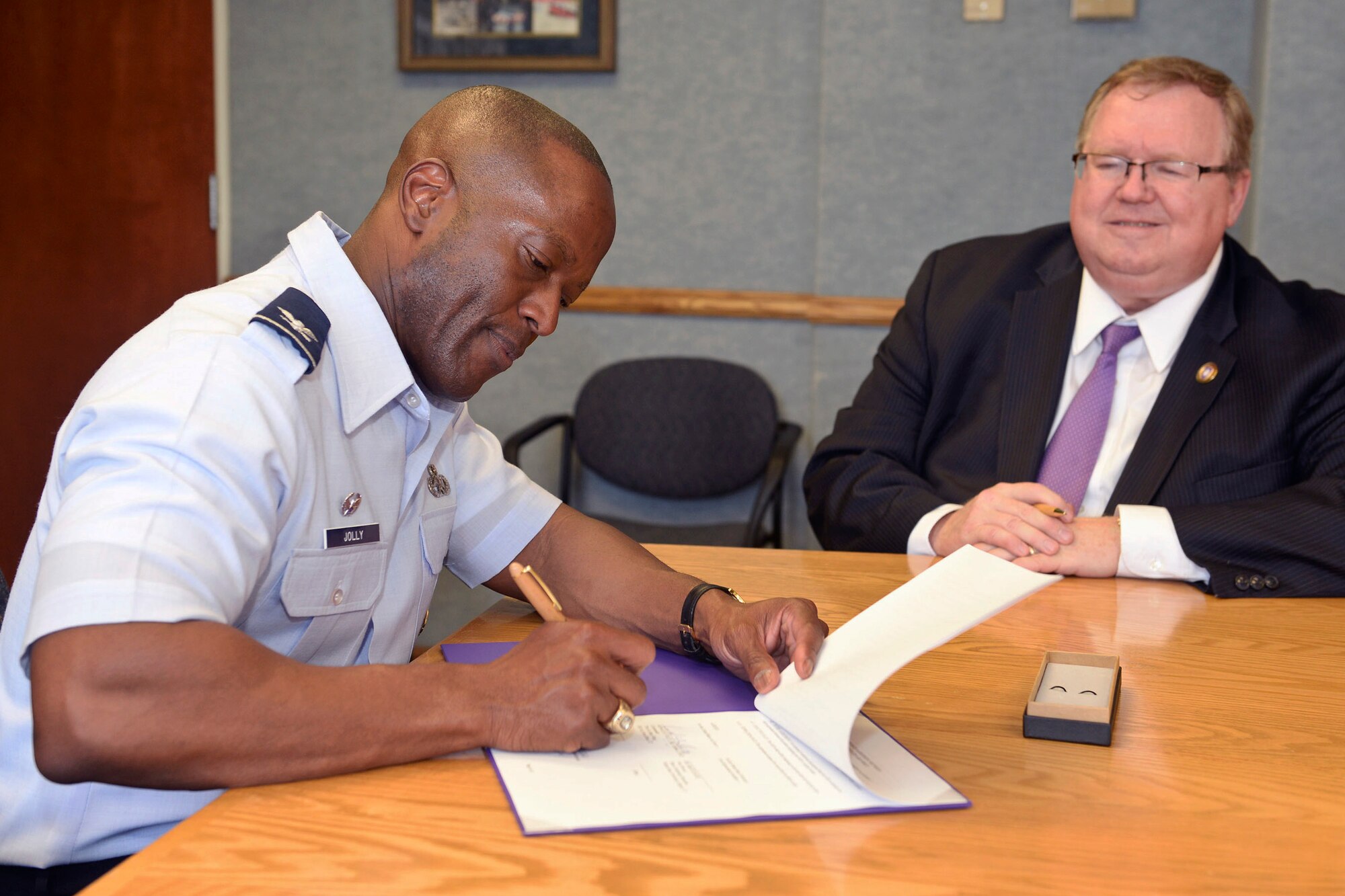 Col. Ronald Jolly, 75th Air Base Wing commander, signs a public/private partnership agreement at Hill Air Force Base, June 22. Looking on is Bruce Davis, Weber State University vice provost and dean of continuing education, who also signed the agreement. The agreement gives WSU’s Law Enforcement Academy students the use of additional training facilities and resources at Hill AFB. (U.S. Air Force photo by 75th Air Base Wing Public Affairs)
