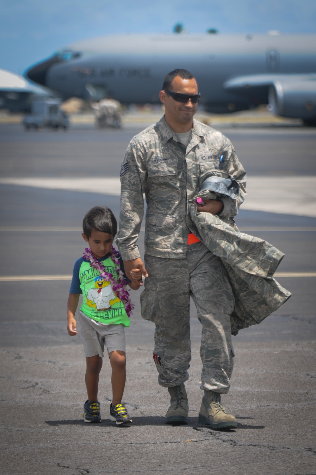 An airman from the Hawaii Air National Guard's 203rd Air Refueling Squadron walks with his son to a hangar at Joint Base Pearl Harbor-Hickam, Hawaii, June 16, 2016. More than 50 service members, three KC-135 Stratotankers, flight and maintenance crews, and other support personnel were deployed for four months as part of an Air Expeditionary Force rotation. (U.S. Air National Guard photo by Airman 1st Class Robert Cabuco/released) 