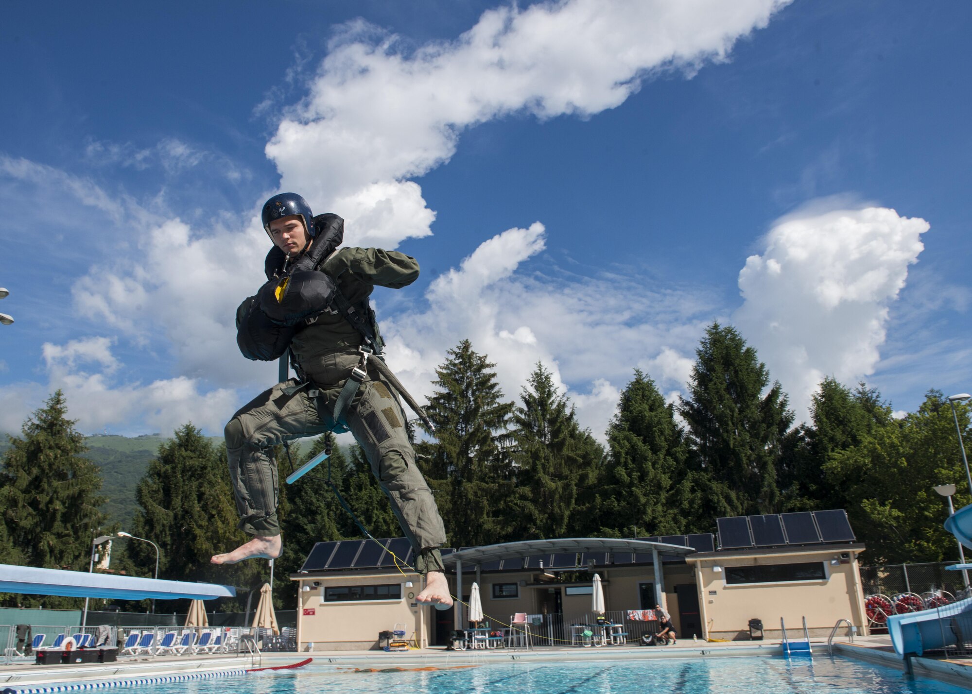 An 555th Fighter Squadron F-16 Fighting Falcon pilot jumps into the pool during water survival training at Aviano Air Base, Italy, June 13, 2016. During the training, participants practiced releasing themselves from a parachute harness while being drug through the water, safely extracting from underneath a parachute, and preforming life raft and recovery device familiarization. (U.S. Air Force photo by Senior Airman Krystal Ardrey/Released)