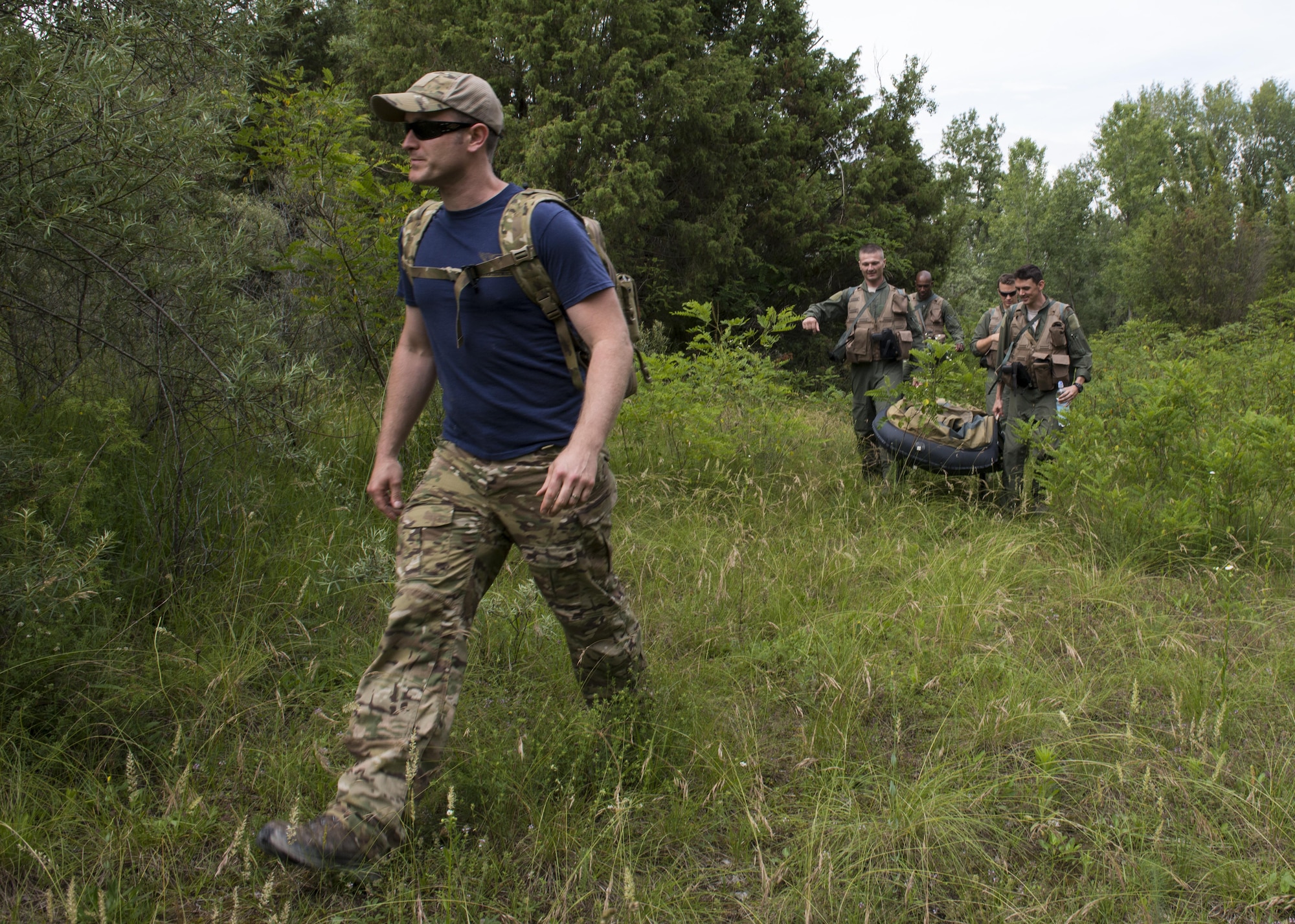 Tech. Sgt. H Jett, 31st Operations Support Squadron NCO in charge of survival, evasion, resistance and escape training, leads combat survival refresher training students through the woods outside of Spilimbergo, Italy, June 14, 2016. The students transported the equipment they would have with them after ejecting from an F-16 Fighting Falcon, evaded simulated enemies and signaled for rescue personnel. (U.S. Air Force photo by Senior Airman Krystal Ardrey/Released)