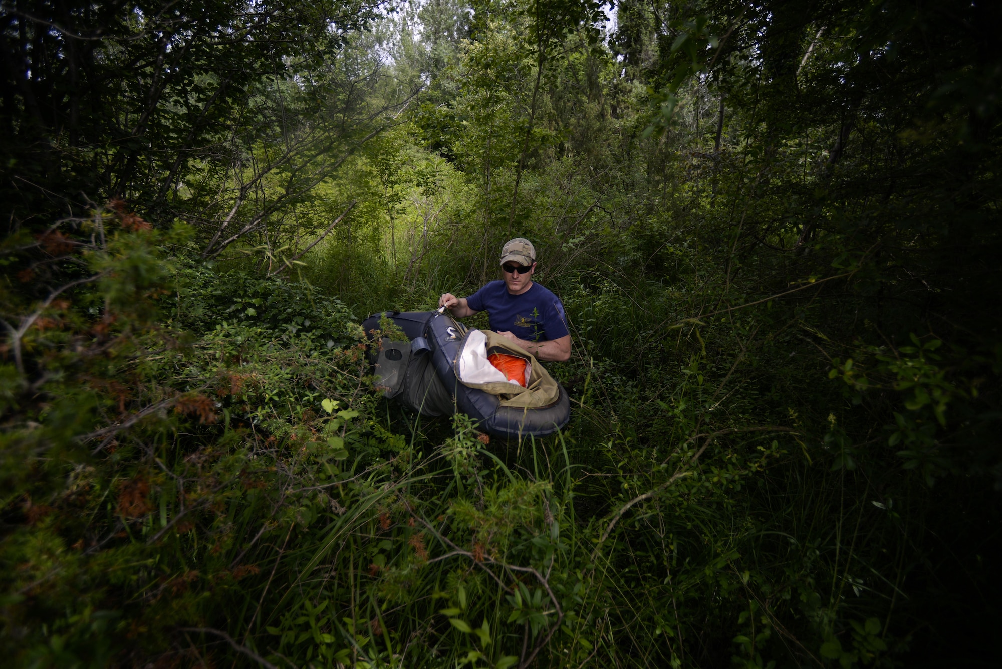 Tech. Sgt. H Jett, 31st Operations Support Squadron NCO in charge of survival, evasion, resistance and escape training, carries an equipment filled life raft through the woods during a combat survival course outside of Spilimbergo, Italy, June 14, 2016. Jett recovered the life raft from where students of the course had left it hidden before practicing evasion maneuvers. (U.S. Air Force photo by Senior Airman Krystal Ardrey/Released)
