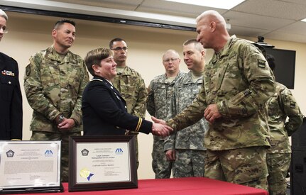 Members of the 80th Training Command’s headquarters company look on as Command Chief Warrant Officer Randy L. Schriver, the 80th TC’s command chief warrant officer, congratulates Capt. Tanya Mayes, an administrative law and military justice attorney assigned to the 80th TC, after Retired Navy Captain Dwain Alexander, a member of the American Bar Association’s Legal Assistance for Military Personnel Distinguished Service Award committee, presented Mayes with the 2015 LAMP award during a ceremony at the Hunter Holmes McGuire VA Medical Center June 10, 2016. Mayes was recognized for leading an effort to establish a free legal assistance clinic for military veterans after she learned that a significant number of patients needed assistance.