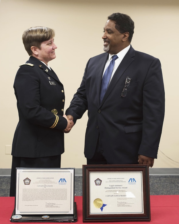 Retired Navy Captain Dwain Alexander, a member of the American Bar Association’s Legal Assistance for Military Personnel Distinguished Service Award committee, congratulates Capt. Tanya Mayes, an administrative law and military justice attorney assigned to the 80th Training Command, after he presented her with the 2015 LAMP award during a ceremony at the Hunter Holmes McGuire VA Medical Center June 10, 2016. Mayes was recognized for leading an effort to establish a free legal assistance clinic for military veterans after she learned that a significant number of patients needed assistance.