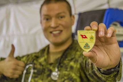 Canadian Army Cpt. Harold Rivera, combat nurse, Garrison Petawawa, Ottawa, Canada, shows the Award for Excellence coin he received from the 91st Training Division, the unit operating the 325th Combat Support Hospital during Combat Support Training Exercise 91-16-02, Fort Hunter Liggett, Calif., June 18, 2016. As the largest U.S. Army Reserve training exercise, CSTX 91-16-02 provides Soldiers with unique opportunities to sharpen their technical and tactical skills in combat-like conditions. (U.S. Army photo by Spc. Fatima Konteh, 367th Mobile Public Affairs Detachment)