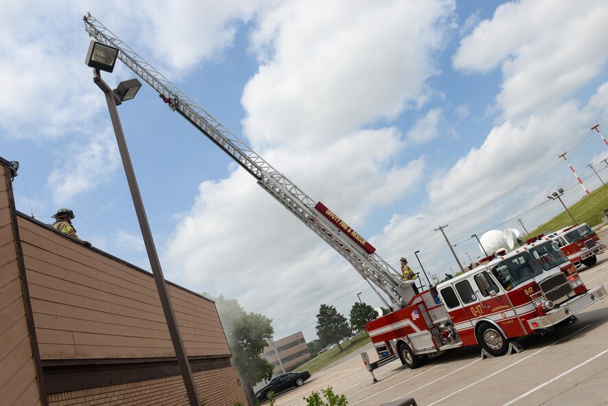 Firefighters assigned to the 55th Civil Engineer Squadron, raise and line up the ladder from a fire truck during a training exercise at building 382 at Offutt Air Force Base, Neb. June 21, 2016. The 55th CES fire department routinely conducts various training scenarios to maintain mission readiness. (U.S. Air Force photo by Zachary Hada)