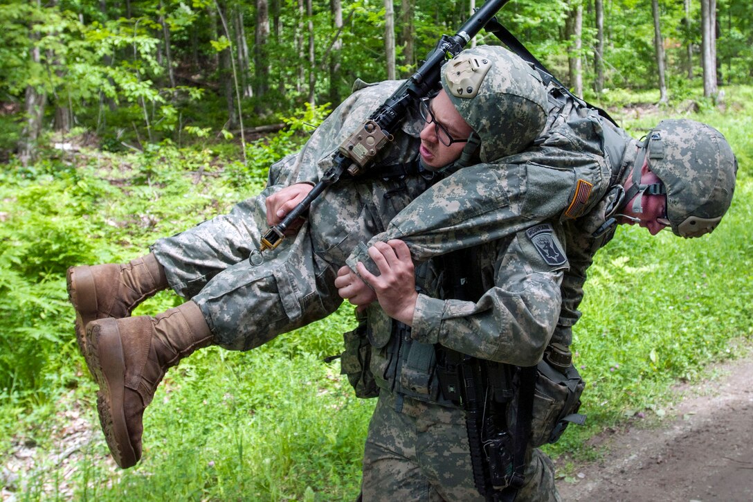 Army Pfc. Daniel Aguilar, standing, carries Army Pfc. Tyler Vance during a medical lane exercise at Camp Ethan Allen Training Site in Jericho, Vt., June 14, 2016. Aguilar and Vance are assigned to the Vermont National Guard’s Company B, 3rd Battalion, 172nd Infantry Regiment, 86th Infantry Brigade Combat Team. Army National Guard photo by Spc. Avery Cunningham