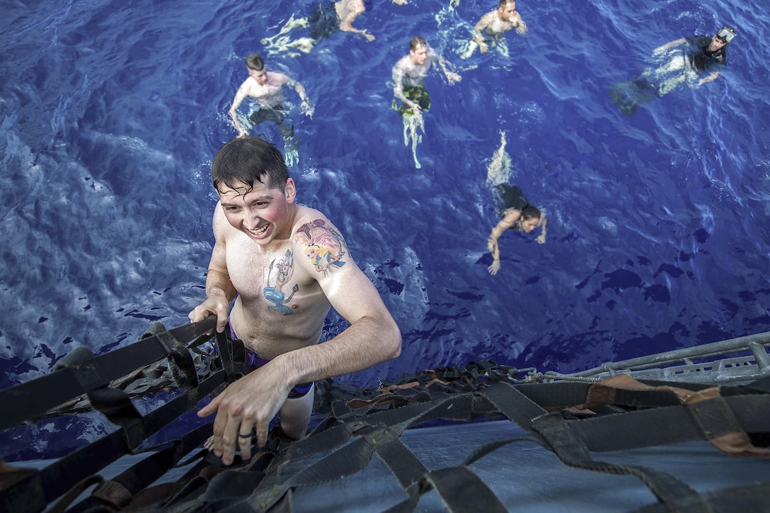 Petty Officer 3rd Class Maxwell Reynolds climbs up a cargo net during a command swim call aboard the USS Mobile Bay in the Pacific Ocean, June 23, 2016. The Bay is operating as part of the John C. Stennis Strike Group and Great Green Fleet on a regularly scheduled 7th Fleet deployment. Navy photo by Petty Officer 2nd Class Ryan J. Batchelder