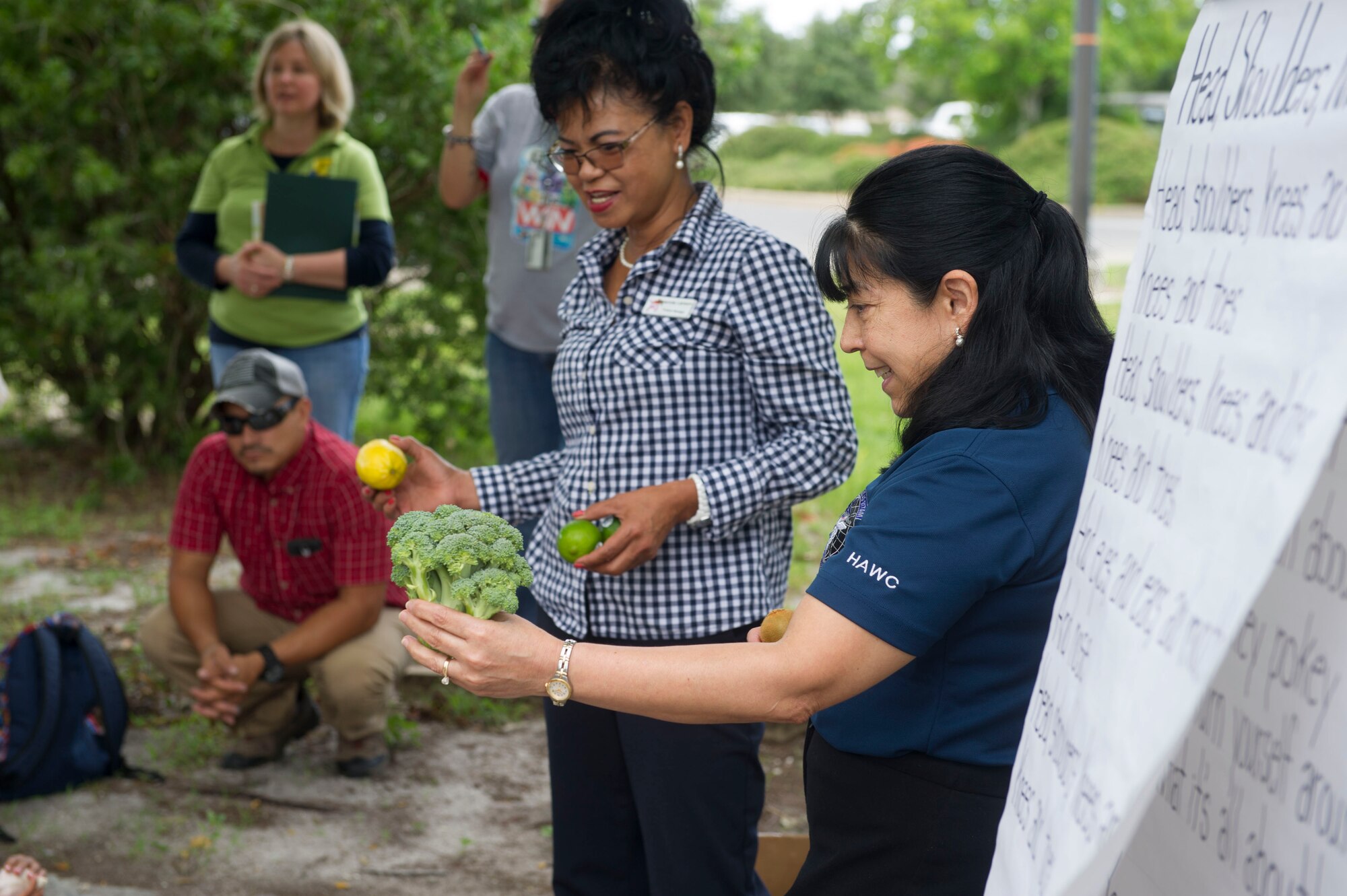 Yolanda Larson, produce manager at the Hurlburt Field commissary, left, and Sandra DeMezzo, a registered dietitian nutritionist with the Health and Wellness Center, show children different fruits and vegetables during a Summer Reading Program event at Hurlburt Field, Fla., June 23, 2016. Week three of the eight-week program focuses on the importance of fruit and vegetable intake as well as physical fitness. (U.S. Air Force photo by Senior Airman Krystal M. Garrett)