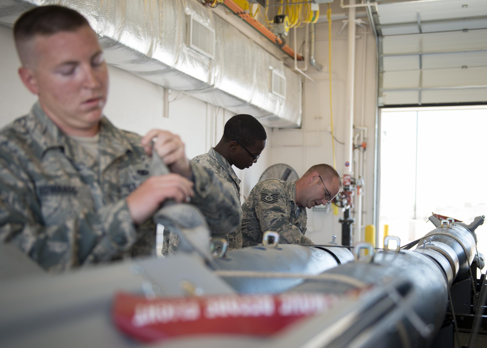 From left to right: Staff Sgt. Aaron, Airman James and Tech. Sgt. Douglas, 49th Maintenance Squadron munitions crew chiefs, secure Guided Bomb Units-12 Paveway II bombs to an ammunition trailer June 21 at Holloman Air Force Base, N.M. The 49th MXS provides GBU-12s and other ammunition to the 49th Wing, as well as a multitude of tenant units in support of training, testing and international flying missions. (Last names are withheld due to operational requirements. U.S. Air Force photo by Senior Airman BreeAnn Sachs)