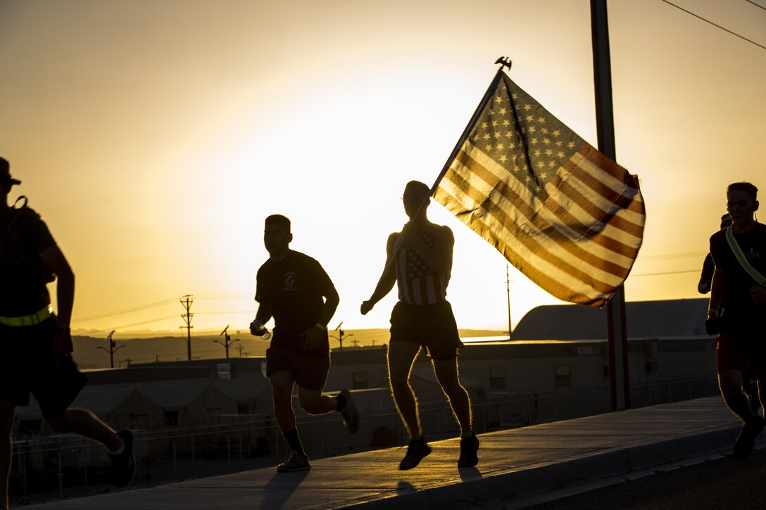 A Marine with Communications Training Battalion, Marine Corps Communication-Electronics School, runs with the national colors during the battalion’s Sunset Run aboard the Marine Corps Air Ground Combat Center, Twentynine Palms, Calif., June 17, 2016.