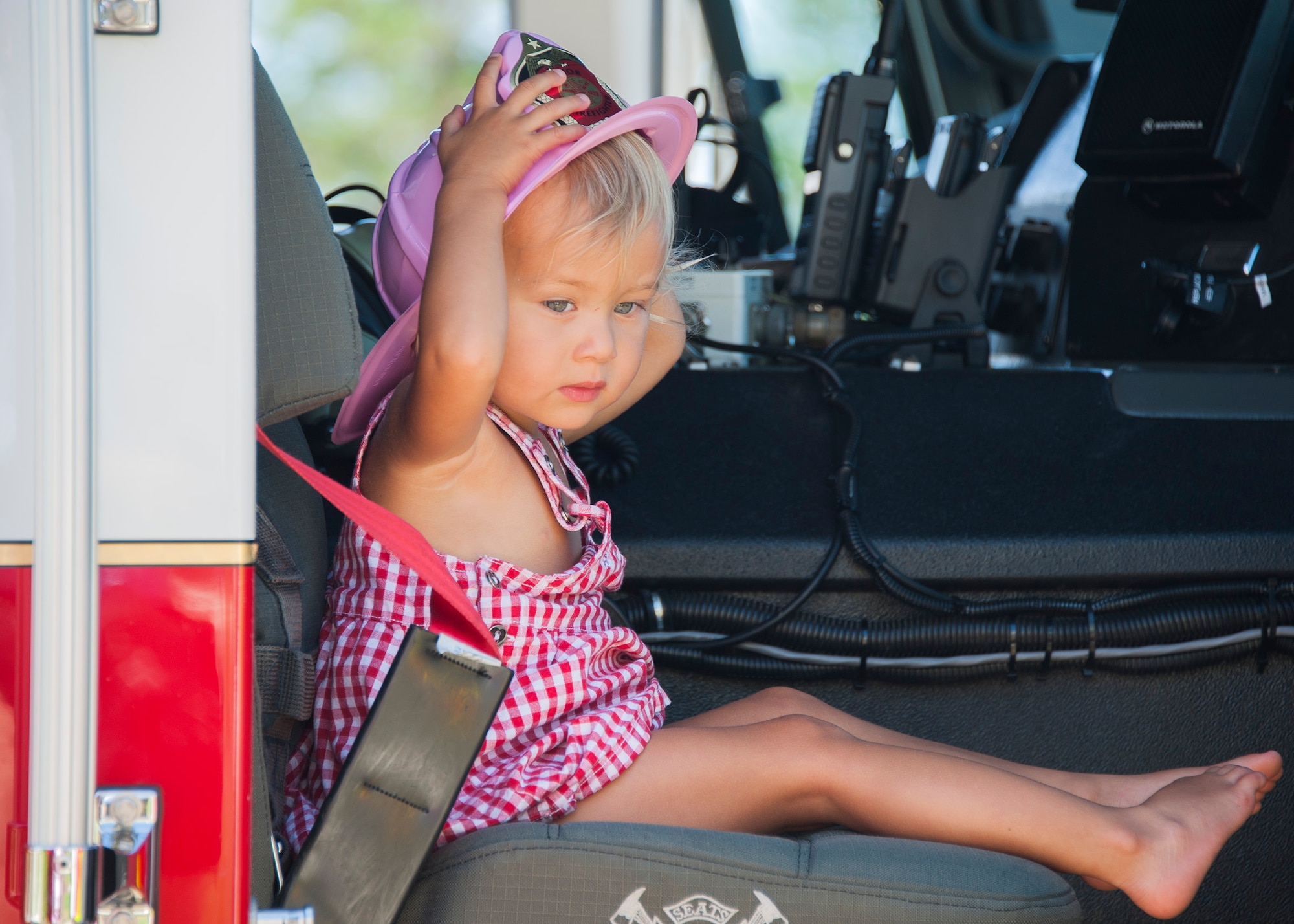 Ondeen Zimmerman, two-years-old, dons her pink firefighter helmet during a visit with fire fighters June 20 at Eglin Air Force Base, Fla. The firefighters helped deliver Zimmerman’s little brother, Luca, in their home on base in the early morning hours of June 13. (U.S. Air Force photo/Ilka Cole) 