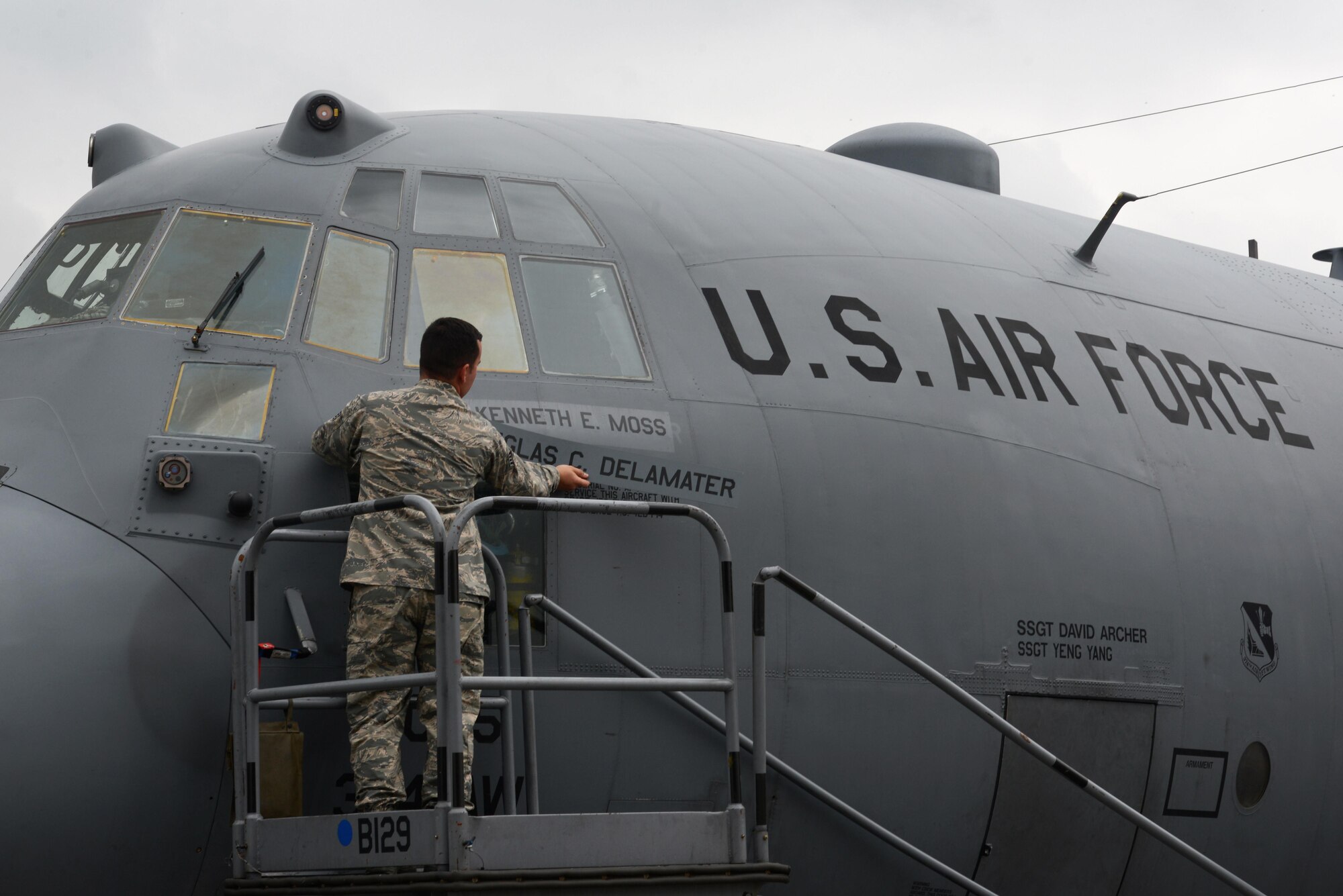 Staff Sgt. George Harlan, 374th Aircraft Maintenance Squadron flying crew chief, unveils the new commander's name, Col. Kenneth Moss, on the 374th Airlift Wing's flagship aircraft during the official wing change of command at Yokota Air Base, Japan, June 24, 2016. Moss took command from Col. Douglas DeLaMater. (U.S. Air Force photo by Staff Sgt. Cody H. Ramirez/Released)