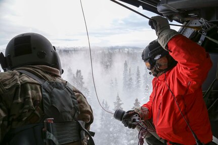 Alaska Air Guardsman Capt. Johh Romspert, a 212th Rescue Squadron combat rescue officer, prepares to be lowered via hoist out of an HH-60 Pave Hawk Helicopter during a training mission held near Mount Susitna Dec. 16.