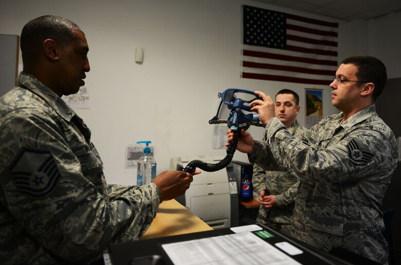 Staff Sgt. Jacob Johnson, 313th Expeditionary Operations Support Squadron aircrew flight equipment member, explains the features of a quick-don mask to Master Sgt. Robert McNeal, 313th EOSS superintendent, at Ramstein Air Base, Germany, June 21, 2016. AFE is responsible for providing life support equipment to Air Mobility Command aircrew transiting through Ramstein en route to deployed locations. (U.S.  Air Force photo/ Airman 1st Class Joshua Magbanua)