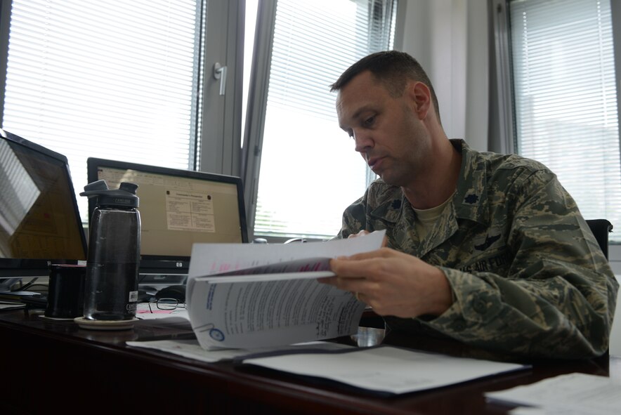 Lt. Col. Lucas Jobe, 313th Expeditionary Operations Support Squadron commander, sifts through documents at Ramstein Air Base, Germany, June 21, 2016. The 313th EOSS is a total force integrated unit consisting of active-duty, reserve and Air National Guard personnel. (U.S.  Air Force photo/ Airman 1st Class Joshua Magbanua)