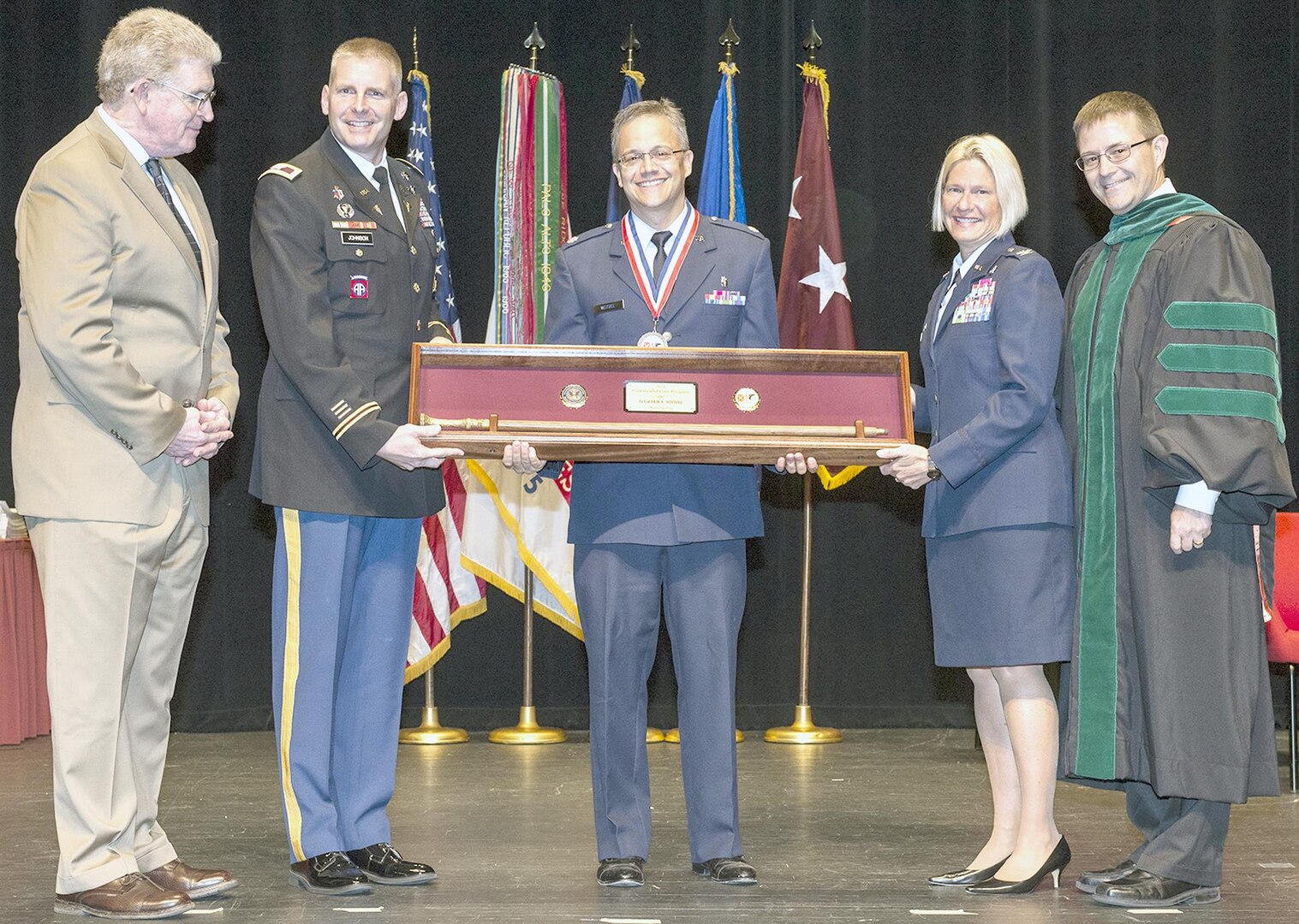 Air Force Lt. Col. Erik Weitzel (center) is presented the Gold Headed Cane by (from left) retired Lt. Gen. Eric Schoomaker; Col. Jeffrey Johnson, BAMC commander; Air Force Col. Rachel Lefebvre, 59th Medical Wing vice commander; and Dr. Woodson “Scott” Jones, San Antonio Uniformed Services Health Education Consortium dean, during the SAUSHEC awards and graduation ceremony in downtown San Antonio June 10. Weitzel, an otolaryngologist, was recognized for excellence in patient care, teaching, clinical research and operational medicine.