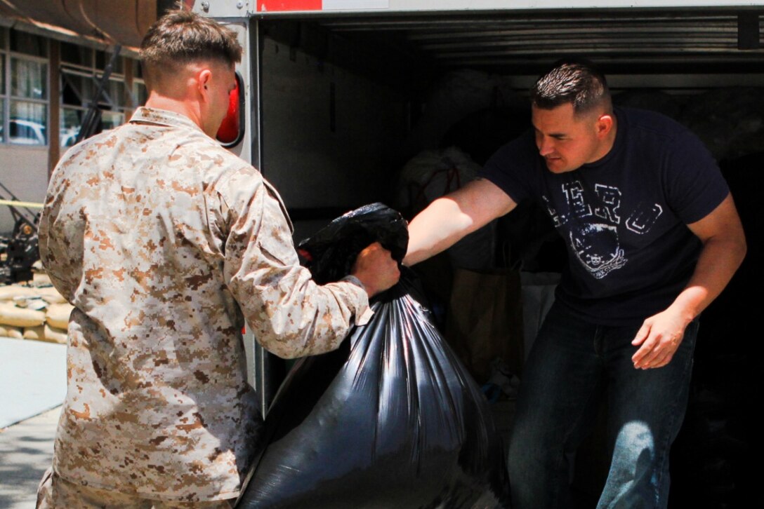Sergeant Phillip Whitener, (left) an assistant platoon sergeant serving with 2nd Battalion, 5th Marine Regiment, and a native of Polk County, Ark., hands a bag of donated clothes to Staff Sgt. David Terryah, a platoon sergeant serving with the battalion, and a native of Fresno, Calif., May 28, 2013. Marines serving with the battalion and their families collected enough supplies to fill a U-Haul truck and a trailer to donate to the victims of the tornadoes that damaged approximately 2,400 homes in and around Moore, Okla., and Oklahoma City, during the week of May 20.

