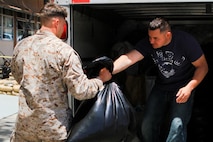 Sergeant Phillip Whitener, (left) an assistant platoon sergeant serving with 2nd Battalion, 5th Marine Regiment, and a native of Polk County, Ark., hands a bag of donated clothes to Staff Sgt. David Terryah, a platoon sergeant serving with the battalion, and a native of Fresno, Calif., May 28, 2013. Marines serving with the battalion and their families collected enough supplies to fill a U-Haul truck and a trailer to donate to the victims of the tornadoes that damaged approximately 2,400 homes in and around Moore, Okla., and Oklahoma City, during the week of May 20.

