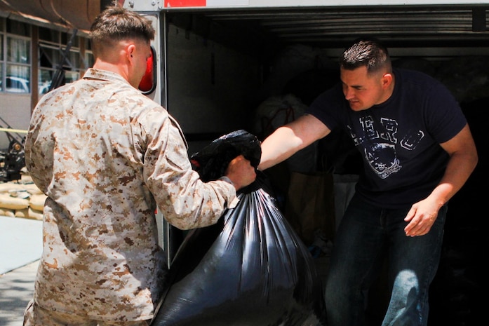 Sergeant Phillip Whitener, (left) an assistant platoon sergeant serving with 2nd Battalion, 5th Marine Regiment, and a native of Polk County, Ark., hands a bag of donated clothes to Staff Sgt. David Terryah, a platoon sergeant serving with the battalion, and a native of Fresno, Calif., May 28, 2013. Marines serving with the battalion and their families collected enough supplies to fill a U-Haul truck and a trailer to donate to the victims of the tornadoes that damaged approximately 2,400 homes in and around Moore, Okla., and Oklahoma City, during the week of May 20.

